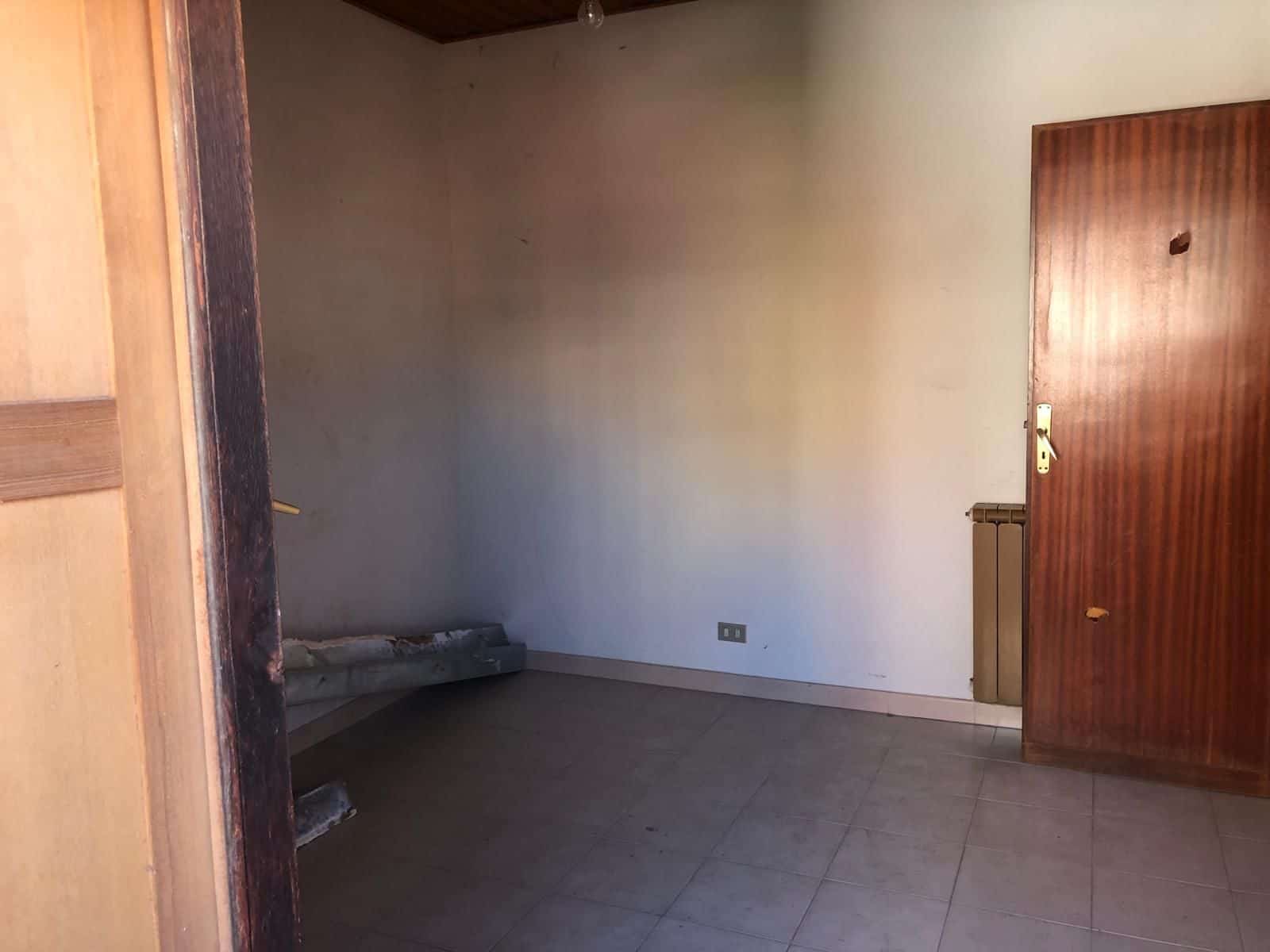 Serratura di sicurezza su porta in legno in un ambiente interno vuoto, pronto per ristrutturazione o arredamento, ideale per soluzioni abitative o commerciali.