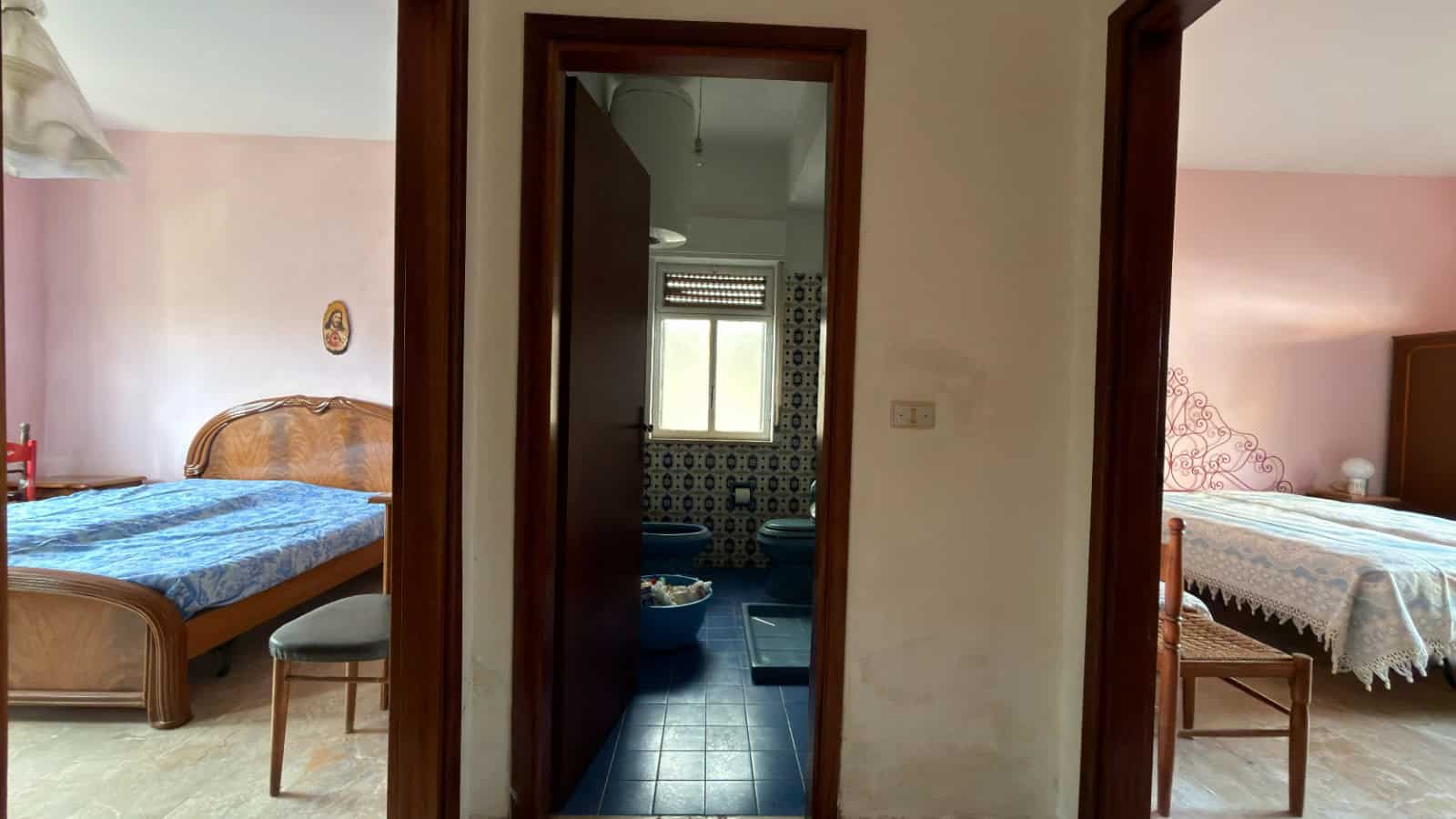 Ampia vista di un ingresso tra due camere da letto in un appartamento, con dettagli di arredo classico e pavimenti in piastrelle, che evidenzia l'ambiente abitativo accogliente e funzionale.