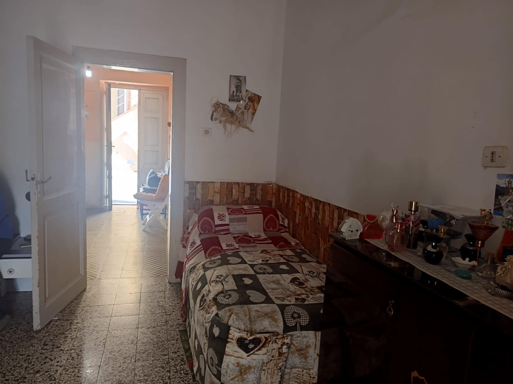 Sedia e tavolo in soggiorno con ingresso luminoso e vista sulla strada, arredamento semplice e funzionale, ambiente accogliente e pratico.
