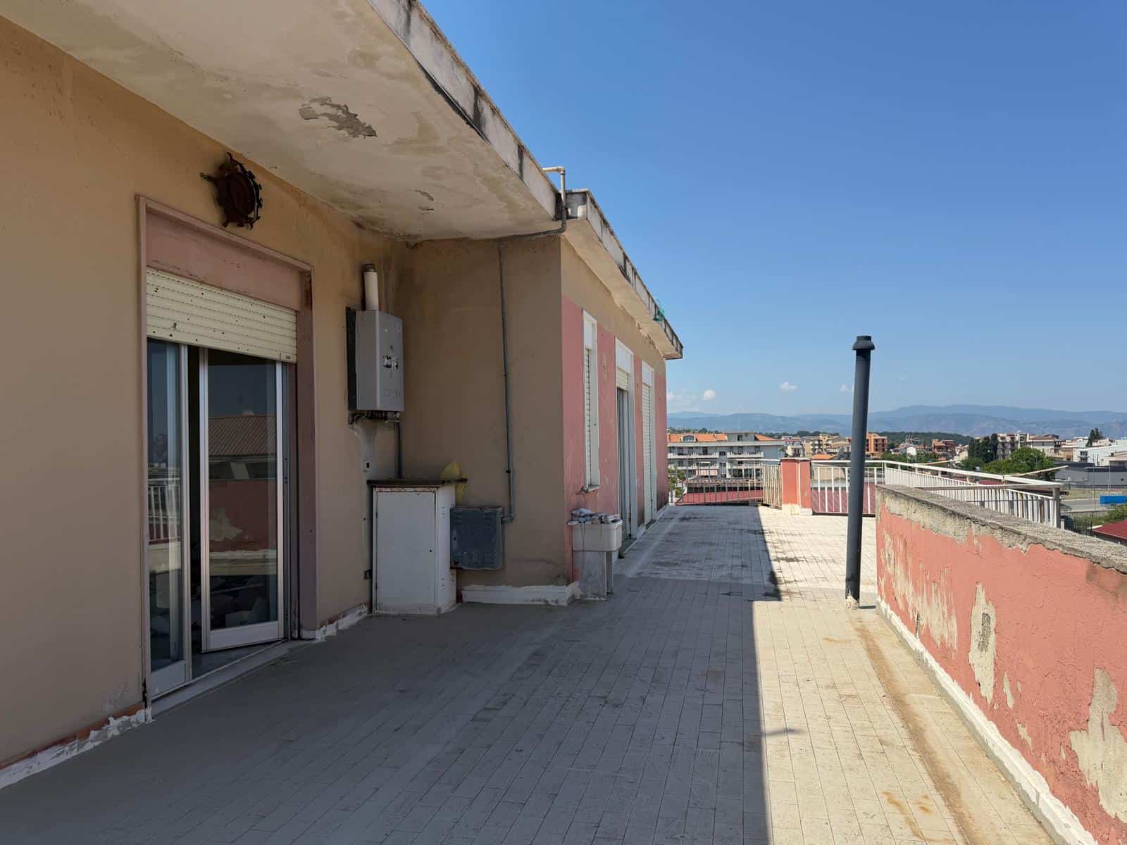 Ampio terrazzo con vista sulla città, ideale per relax e socializzazione, con pavimentazione in piastrelle e parapetto in muratura. Perfetto per creare uno spazio esterno vivibile e panoramico.