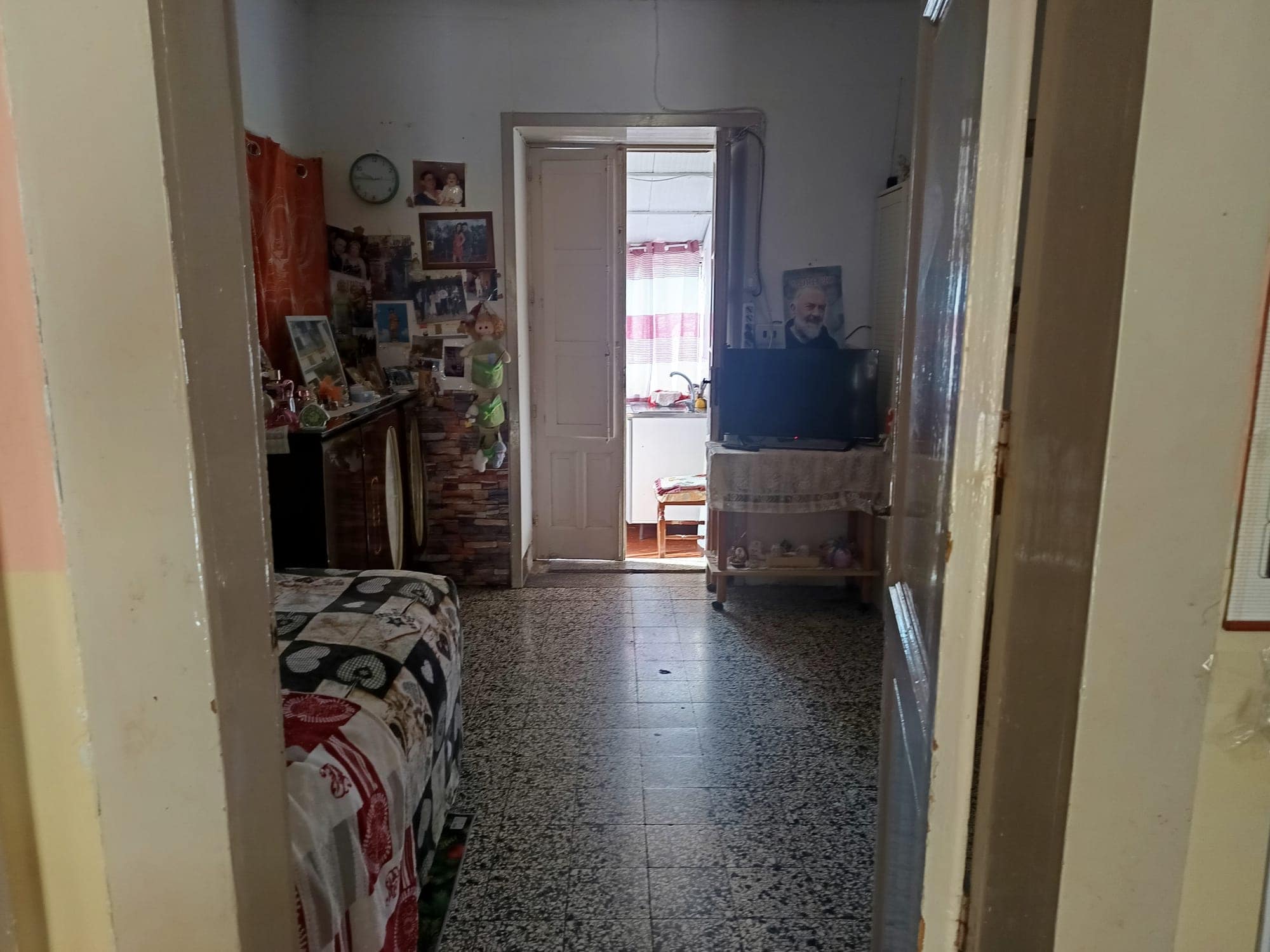 Interno di un appartamento con soggiorno e ingresso, arredato con mobili e decorazioni, vista verso una stanza luminosa.