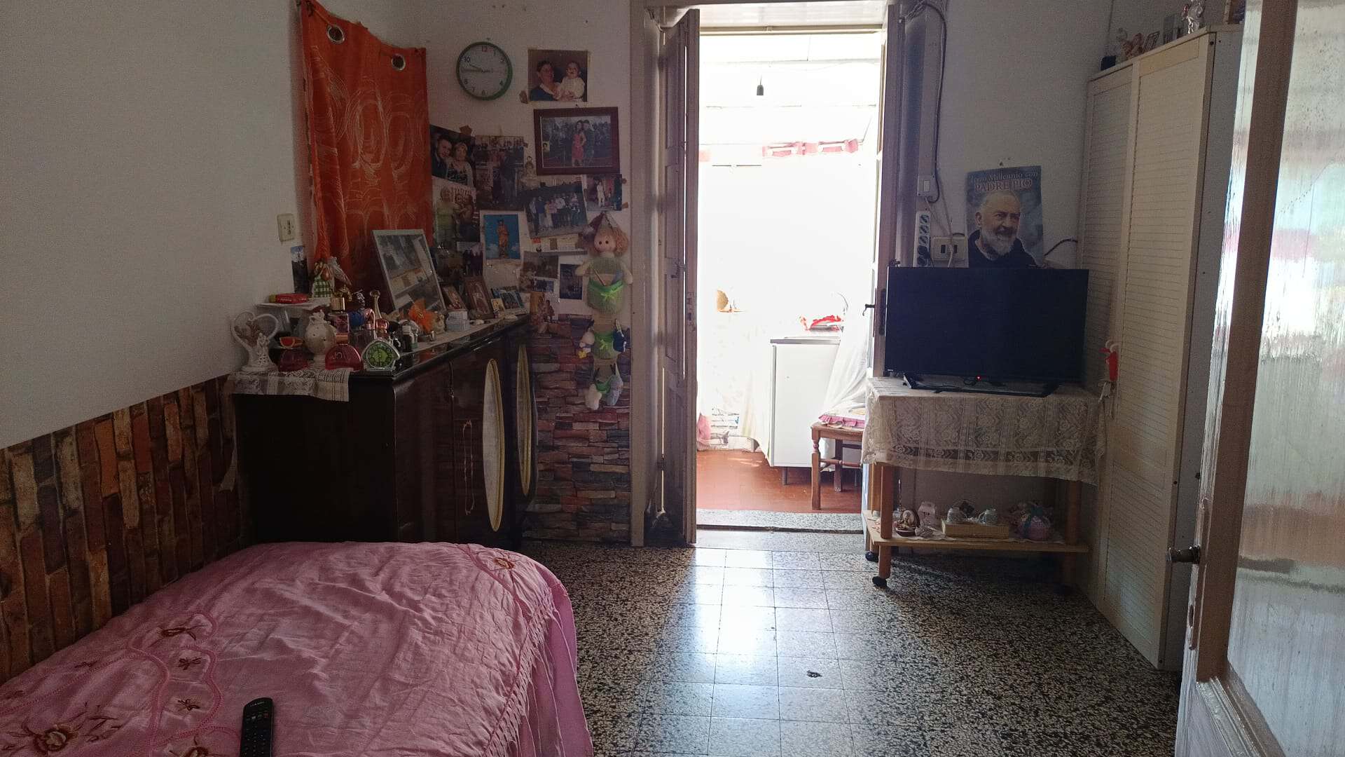 Ampio soggiorno con camera da letto, arredato con mobili pratici e decorazioni personali, luce naturale proveniente dalla porta finestra, ideale per chi cerca soluzioni abitative accoglienti e funzion.