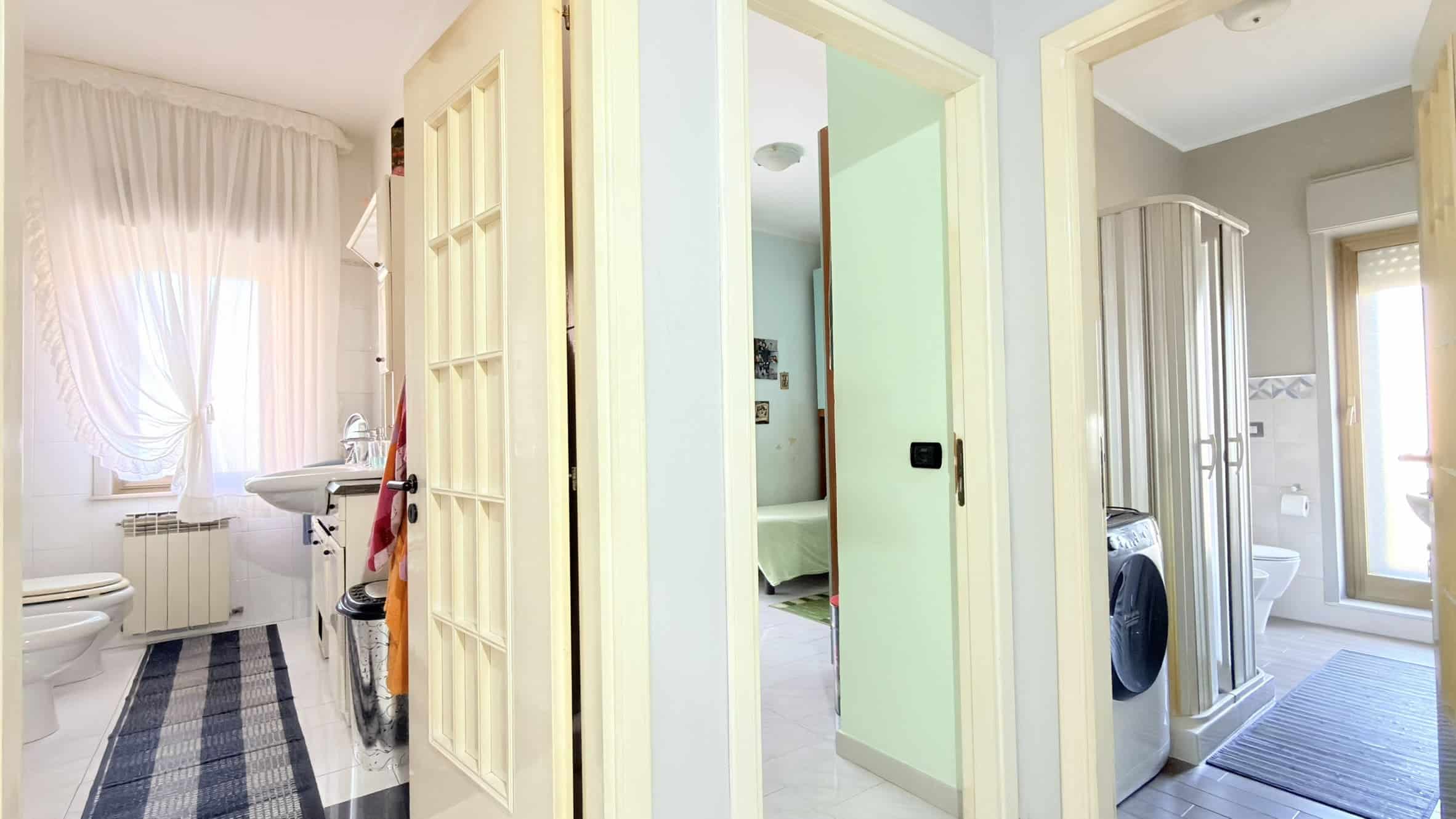 Spazio lavanderia e bagno con doccia, lavatrice e asciugatrice in un appartamento moderno, luminoso e ben arredato, ideale per famiglie o coppie che cercano comfort e funzionalità in una casa in Itali.