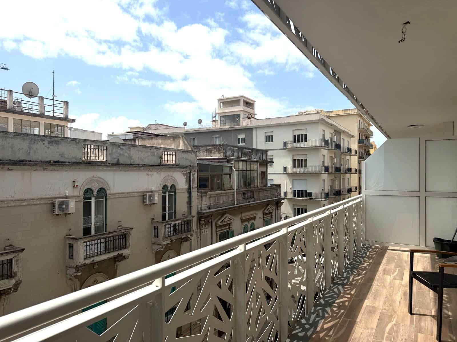 Balcone di un appartamento con vista su edifici storici e cielo nuvoloso, in un contesto urbano italiano.