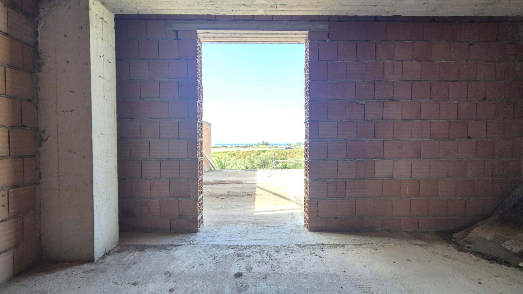 Cancello di un edificio in costruzione con vista panoramica all'aperto, mattoni rossi e struttura in fase di completamento, pronto per essere rifinito e arredato.