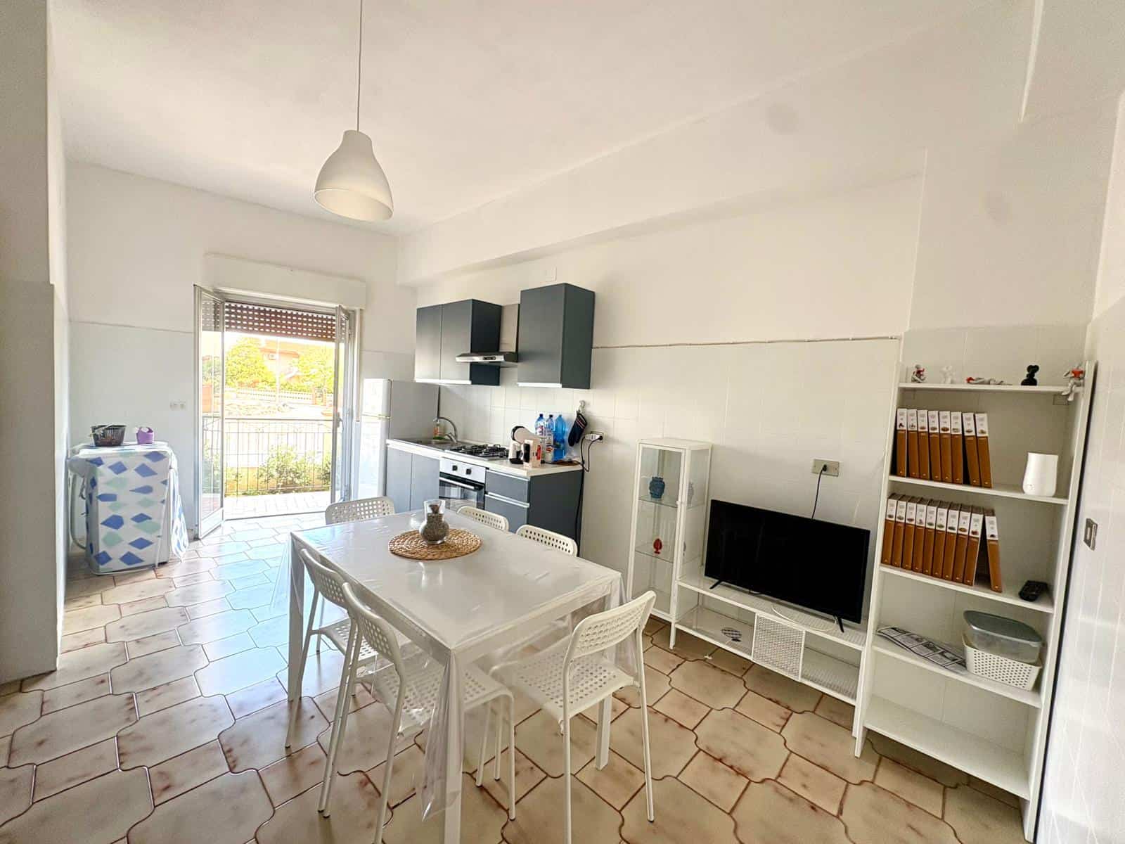 Cucina moderna e luminosa con mobili bianchi e accessori blu, vista su balcone con vista panoramica, ideale per soggiorni confortevoli e funzionali.