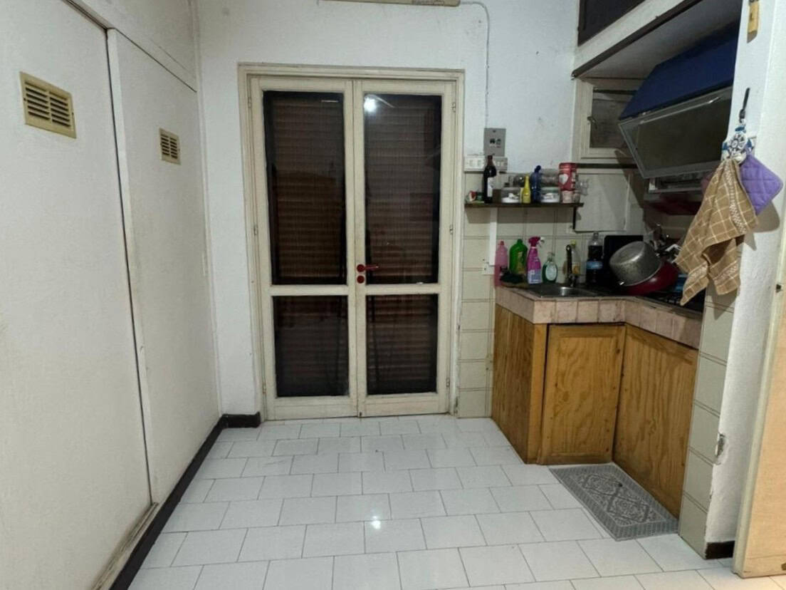 Porte in vetro e cucina con armadietti in legno, ambiente domestico semplice e funzionale, vista da dentro la cucina con accesso a un'area esterna o balcone.