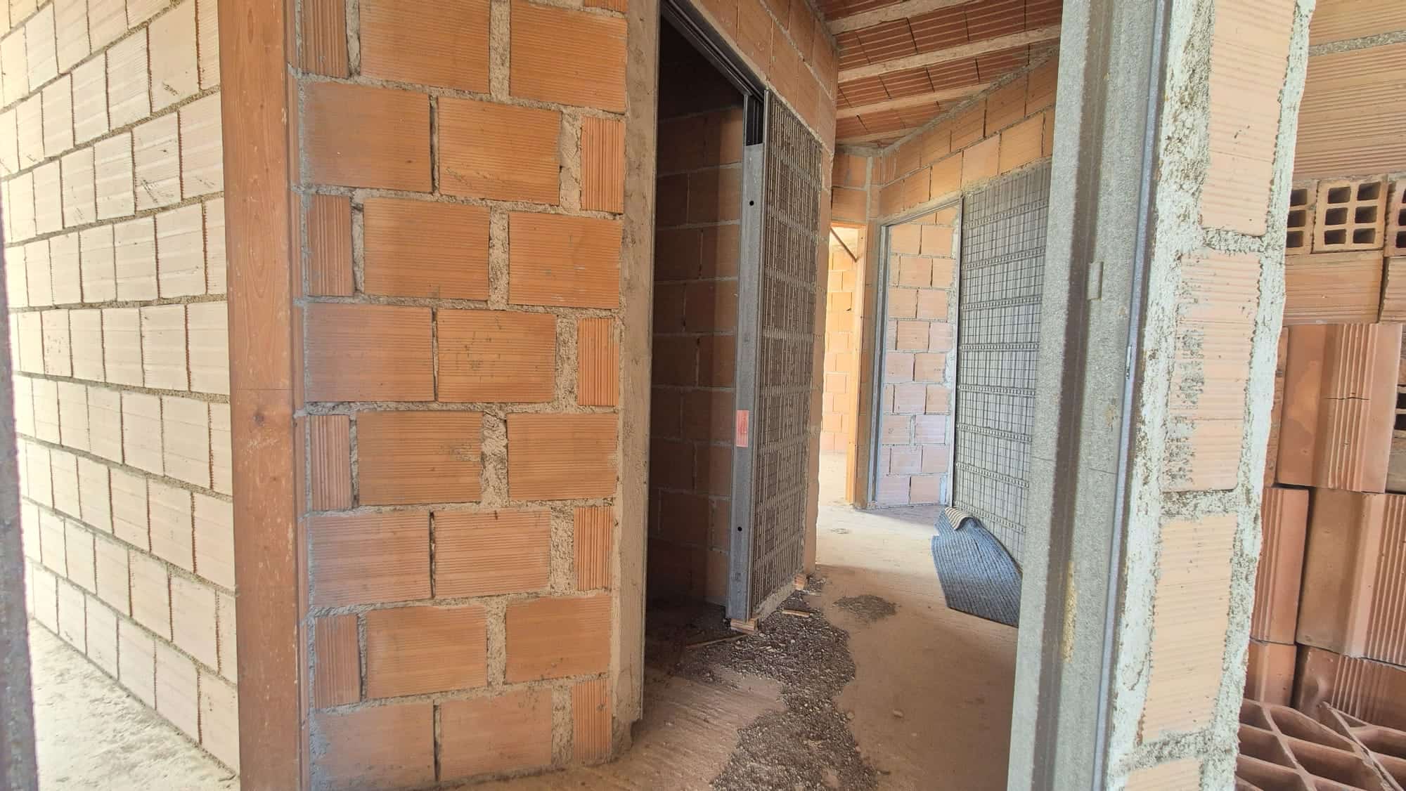Ampia vista di un interno in costruzione con pareti in mattoni rossi e strutture in cemento, pronto per la fase di finitura e ristrutturazione.