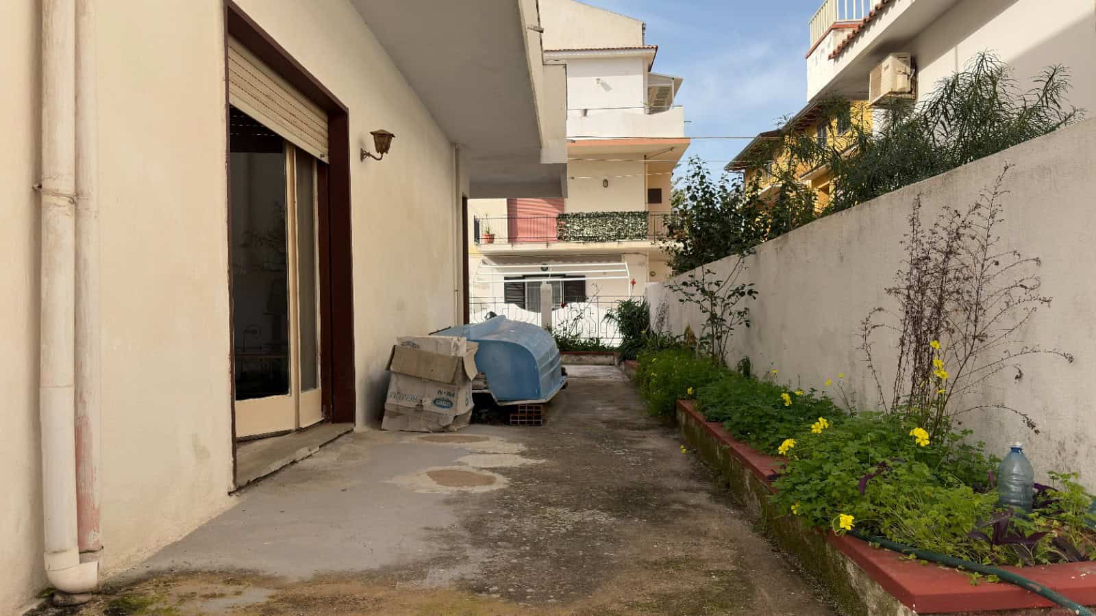Ampio cortile esterno di una casa moderna con piante e fiori, spazio per il relax e la vita all'aperto, ideale per famiglie e residenti che cercano tranquillità e natura in città.