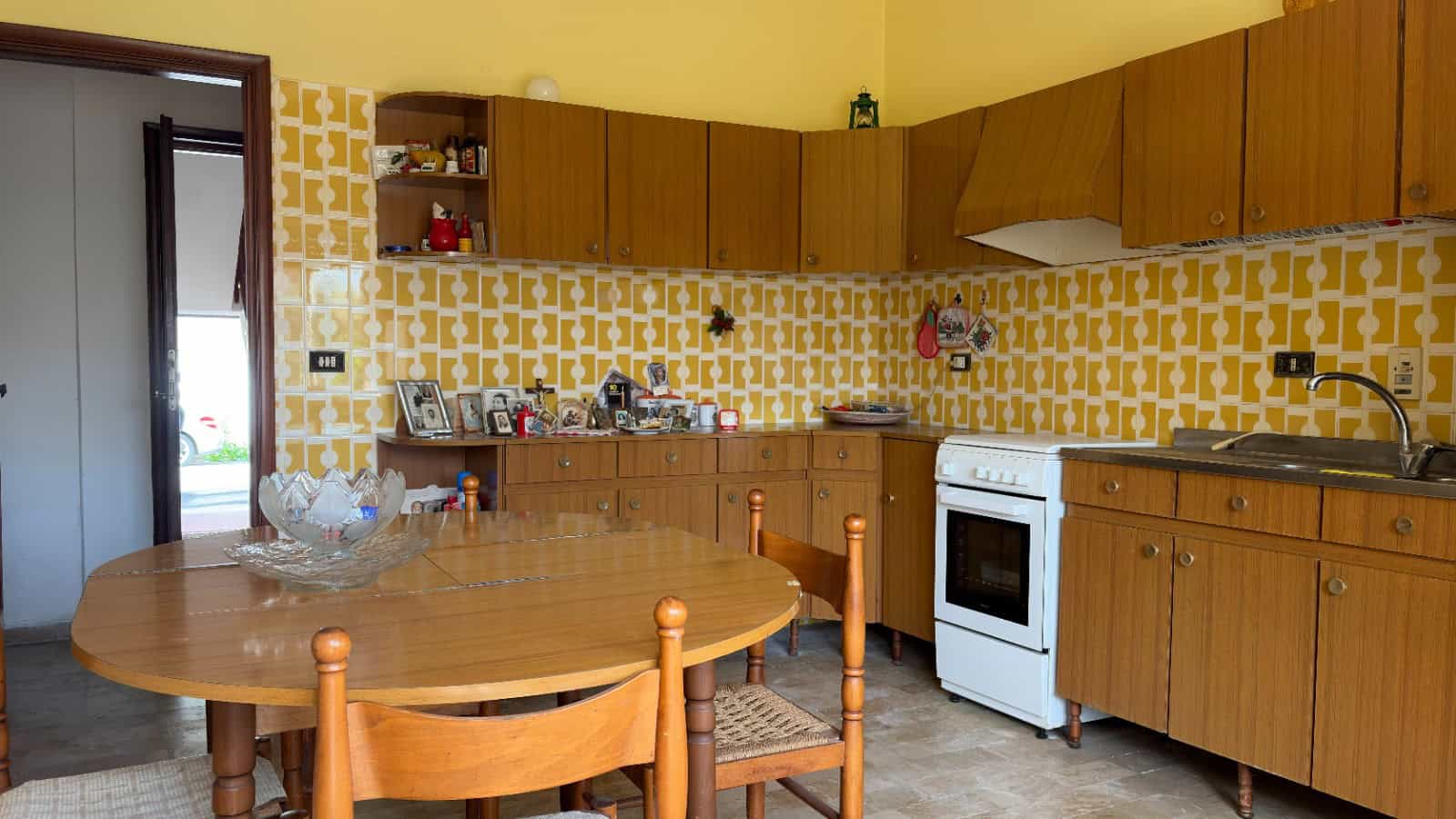 Pannello di cucina in legno con mobili rustici, piano cottura e lavabo, decorata con piastrelle gialle e bianche, ambiente accogliente e funzionale per la preparazione dei pasti.