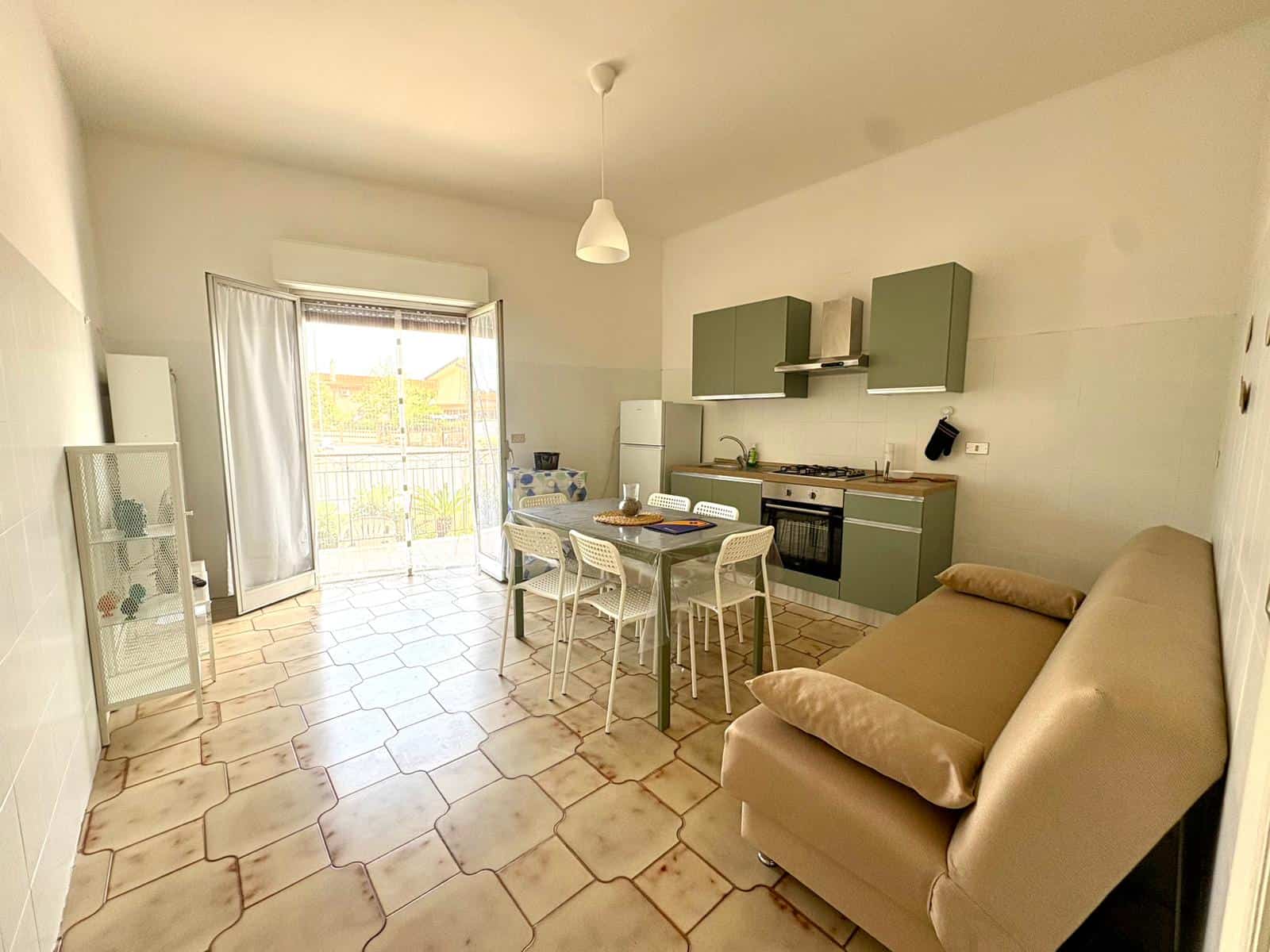 Cucina moderna e luminosa con soggiorno, tavolo da pranzo e accessori, in un appartamento ben arredato e accogliente.