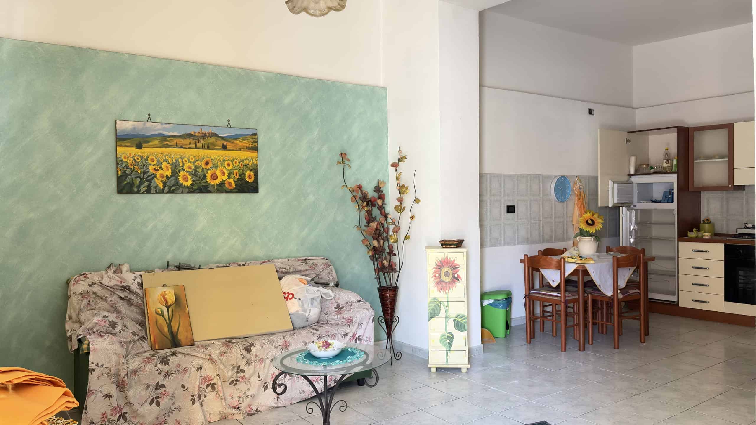 Ampia zona soggiorno con divano floreale, decorazioni colorate e ambiente luminoso, ideale per relax e convivialità in un appartamento in affitto a NextCasa.