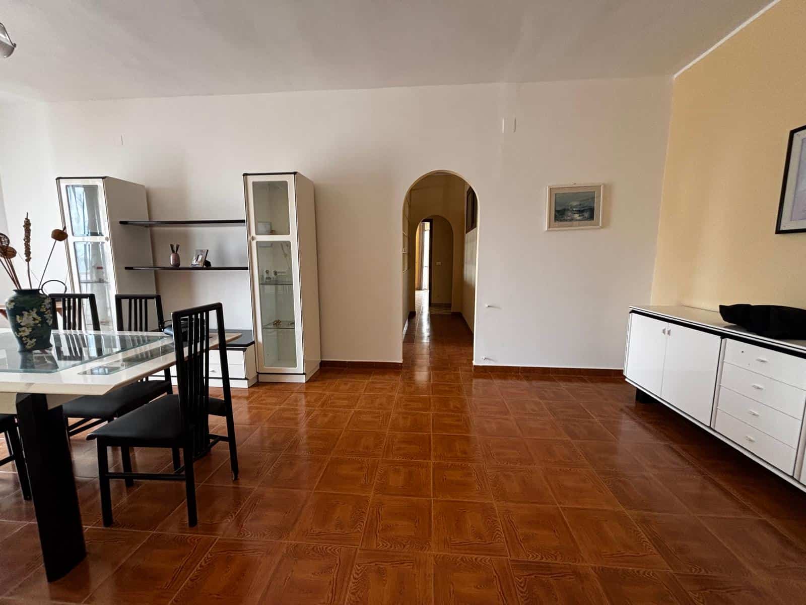 Ampia sala da pranzo con tavolo e sedie nere, armadiature bianche e pareti decorate con quadri, ambiente luminoso e accogliente, ideale per vivere momenti conviviali in casa.
