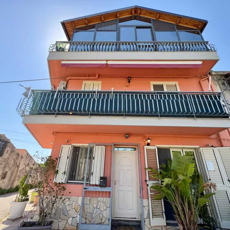 Casa moderna a tre piani con balconi e terrazza panoramica, facciata rosa e dettagli in pietra, situata in zona residenziale soleggiata.