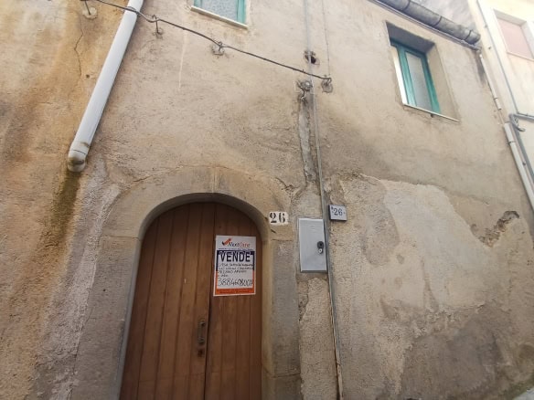 Casa storica in vendita con porta in legno e pareti in pietra, situata in zona urbana.