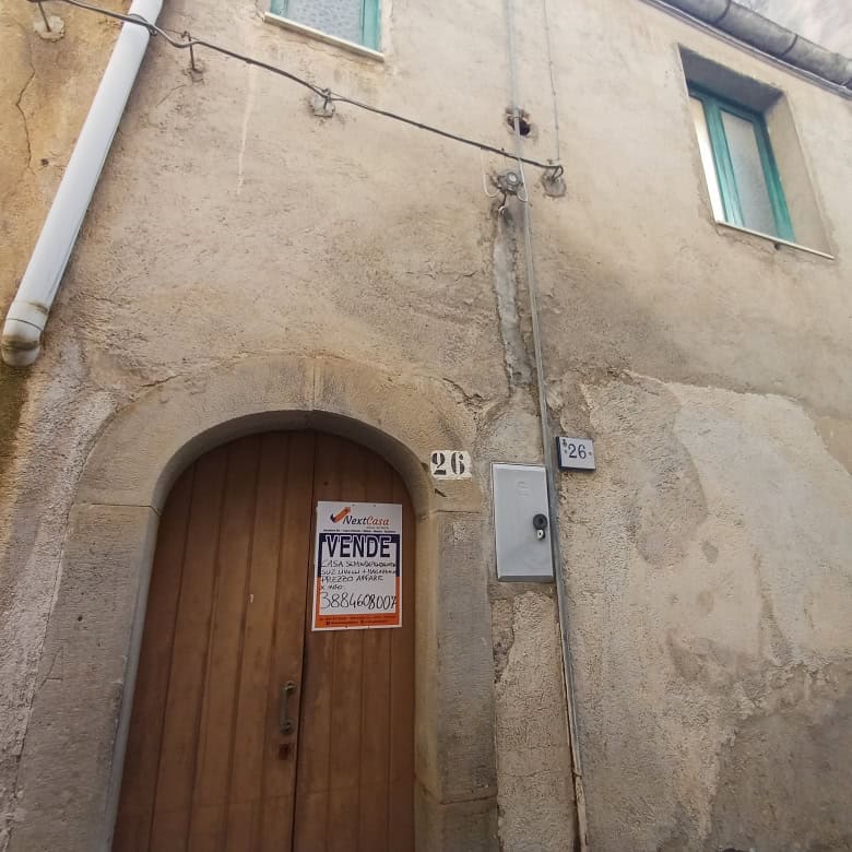 Casa storica in vendita con porta in legno e pareti in pietra, situata in zona urbana.