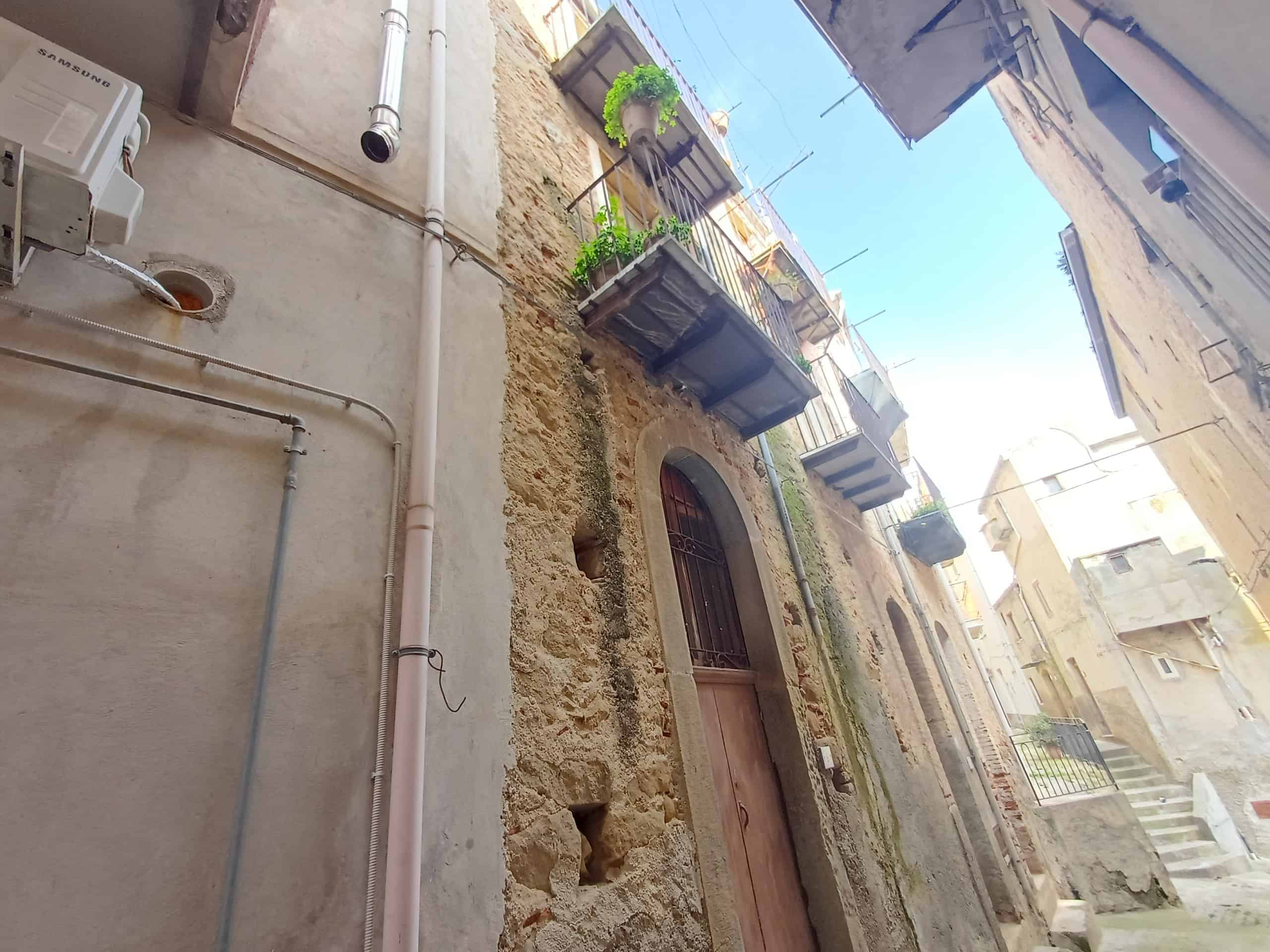 Ville storiche di Napoli con edifici antichi e balconi fioriti, mostra un angolo di quartiere con facciate in pietra, balconi decorati con piante e un'atmosfera autentica e tradizionale.
