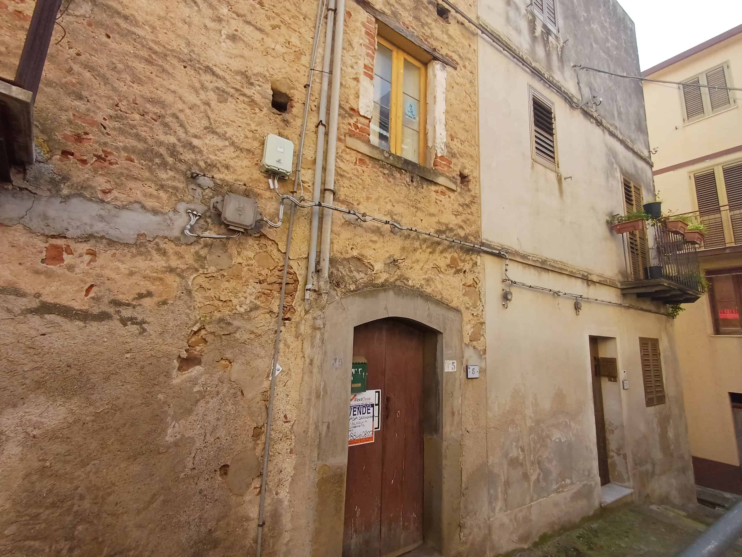 Casa rustica in pietra con porta in legno e finestre con infissi gialli.