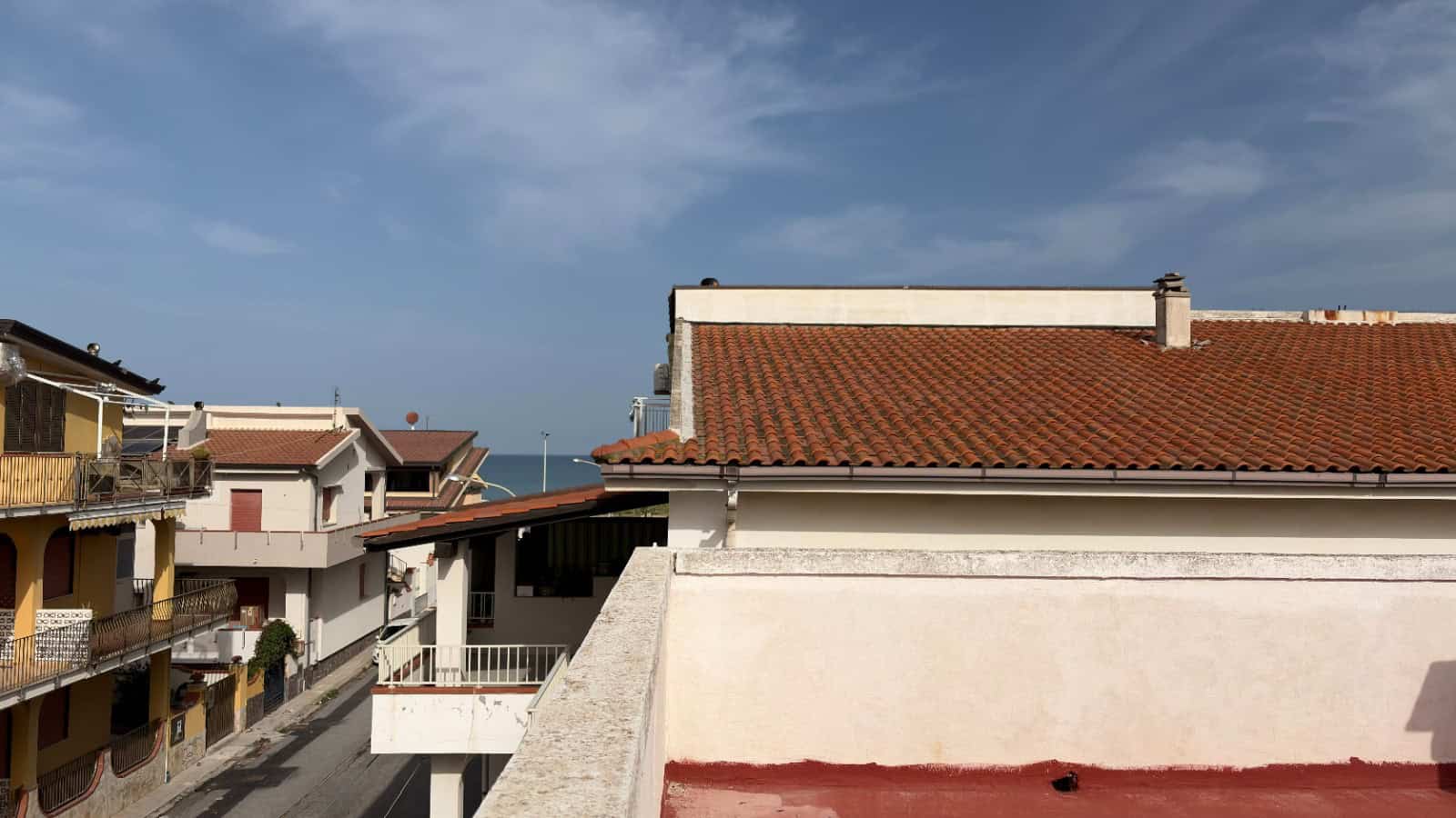 Ampio panorama di case residenziali con tetti in terracotta e balconi, vista sul cielo sereno, in un quartiere tranquillo vicino al mare, ideale per chi cerca immobili in vendita o affitto in zona res.