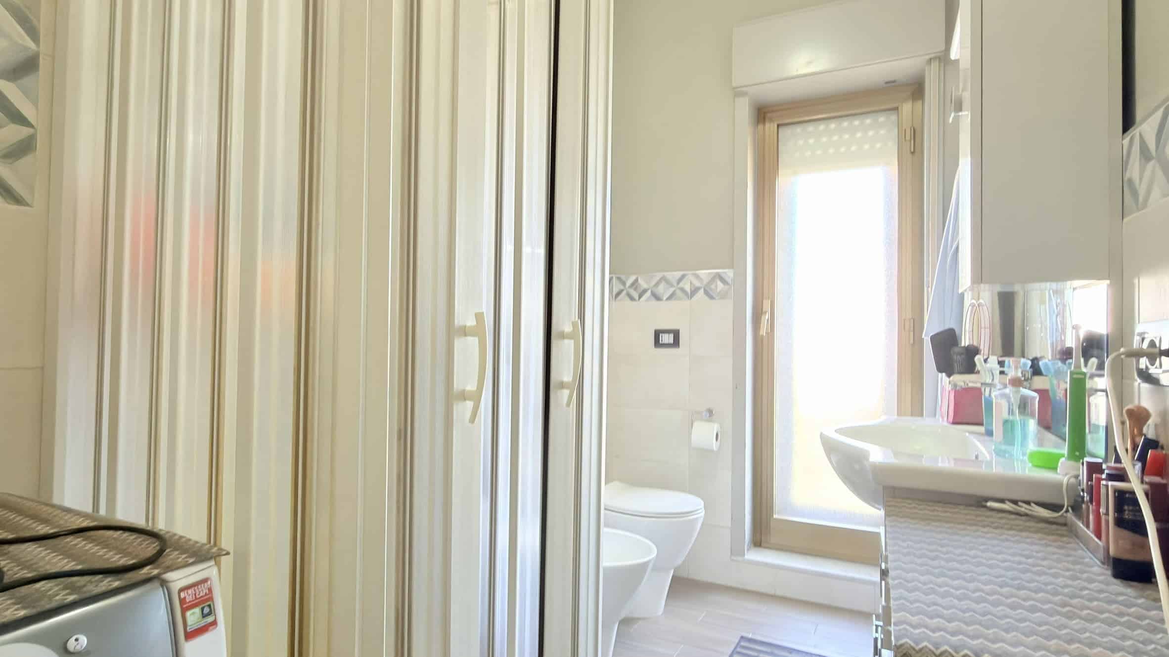 Spazzolino da denti, prodotti per l'igiene e lavabo in bagno luminoso con finestra, arredamento moderno e dettagli pratici per la cura personale.