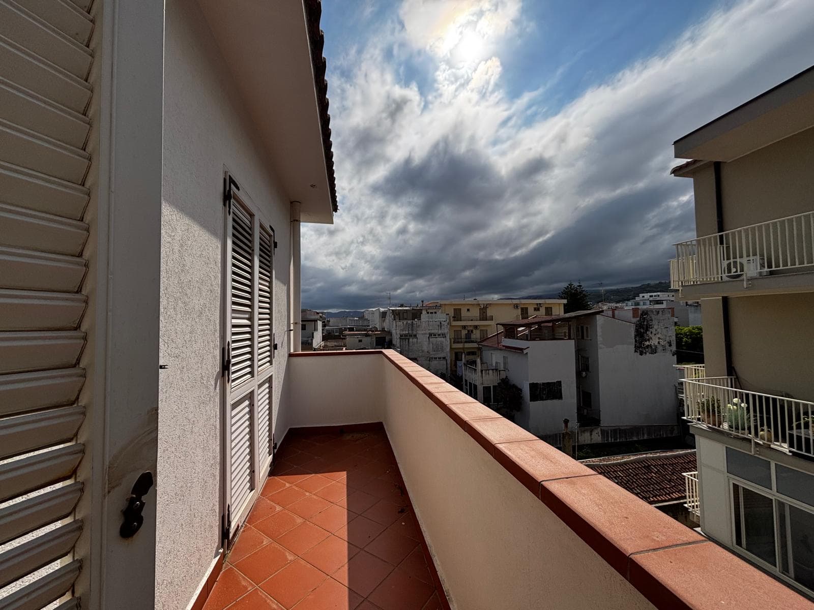 Ampio balcone con vista sulla città e sul cielo nuvoloso, ideale per relax e momenti all'aperto, in un appartamento moderno vicino a servizi e attrazioni locali.