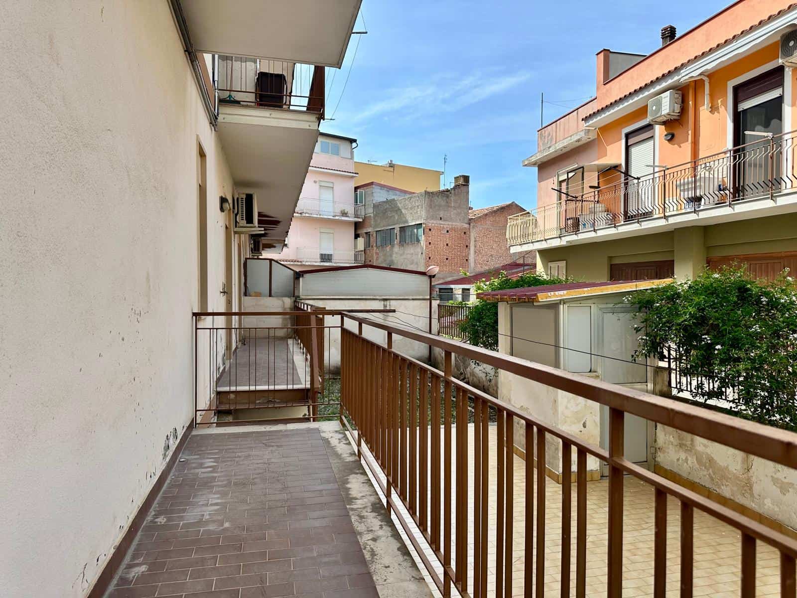 Balcone di un appartamento in zona urbana con vista su edifici residenziali e cielo sereno, ideale per immobili in vendita o affitto a NextCasa.