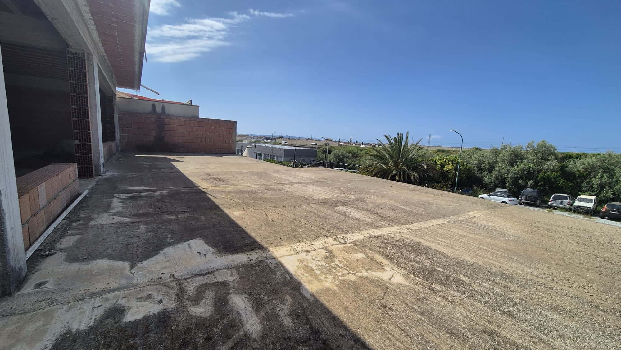 Ampio terrazzo esterno con vista panoramica, pavimentato in cemento, ideale per relax e attività all'aperto, vicino a aree verdi e parcheggi.
