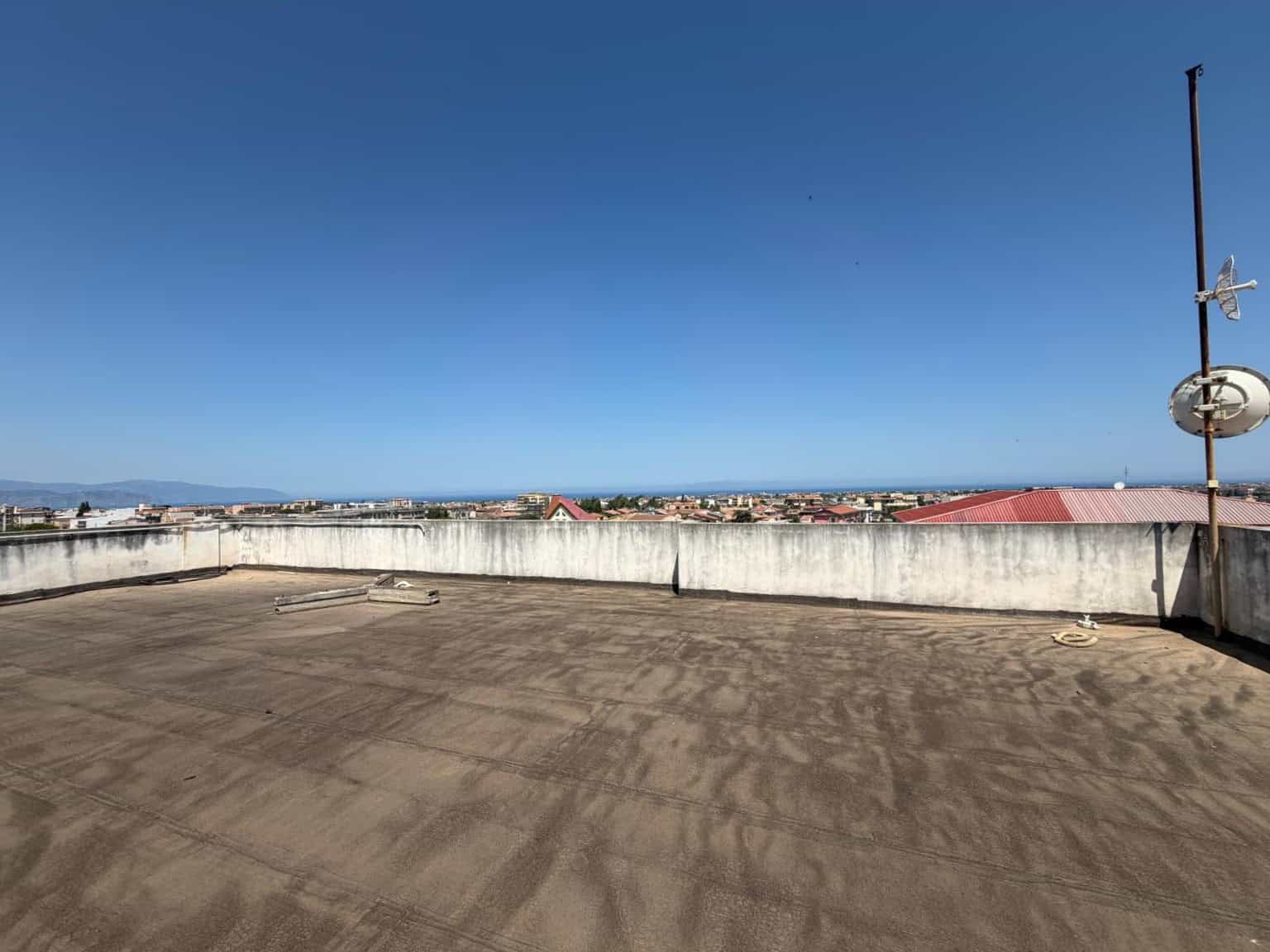 Il tetto di un edificio con vista panoramica sulla città e il cielo sereno, con attrezzature per la comunicazione come antenna e parabola.