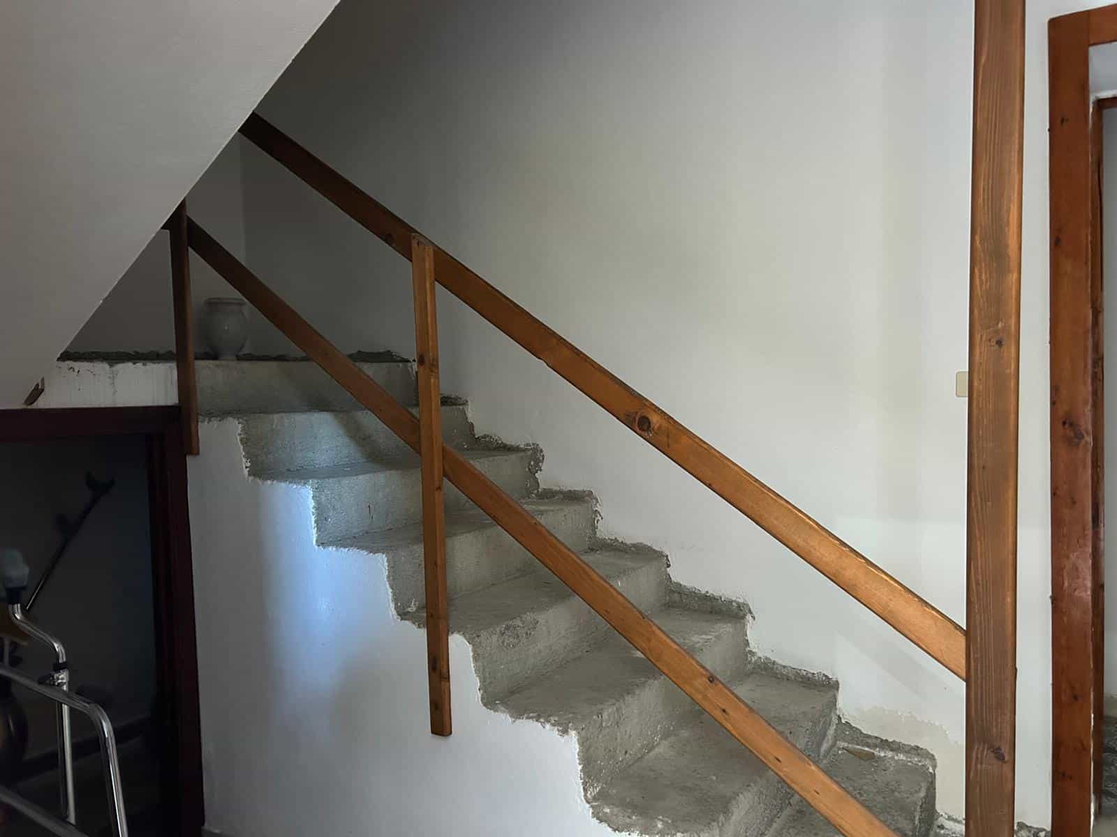 Scale interna in fase di ristrutturazione con ringhiera in legno, pronta per essere rifinita e completata. Ideale per case in costruzione o ristrutturazione, con potenziale di personalizzazione e desi.
