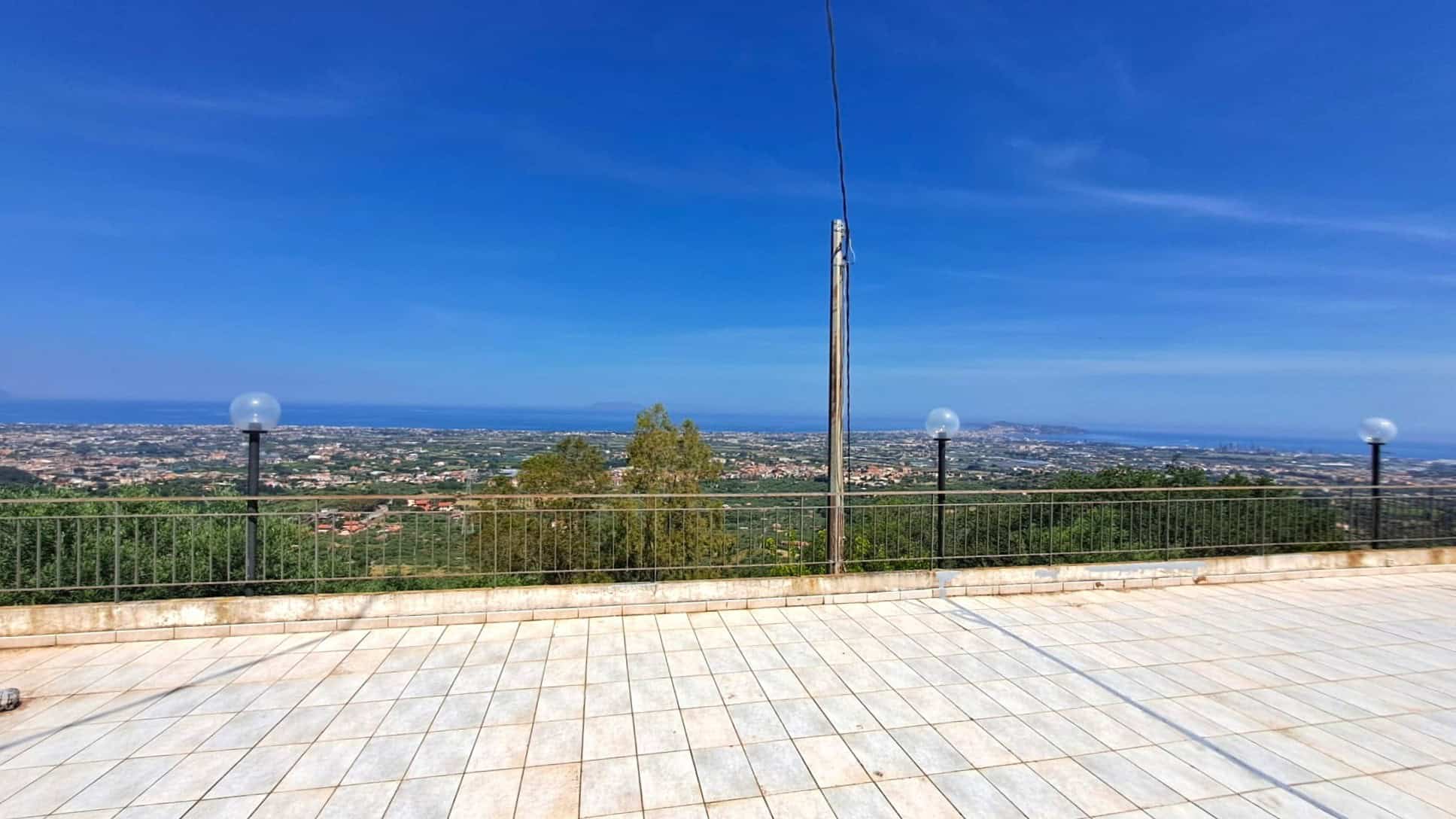 Ampia terrazza panoramica con vista sulla città e sul paesaggio circostante, illuminata da lampioni eleganti e un cielo sereno, ideale per relax e momenti all'aperto.