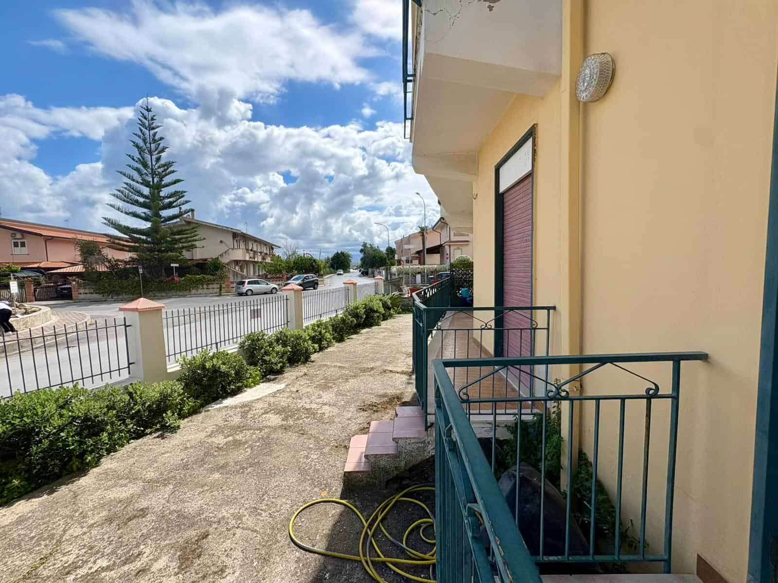 Pannello solare installato sul tetto di una casa residenziale in un quartiere tranquillo, con cielo sereno e nuvole bianche, strada asfaltata e giardino ben curato, rappresentando efficienza energetic.