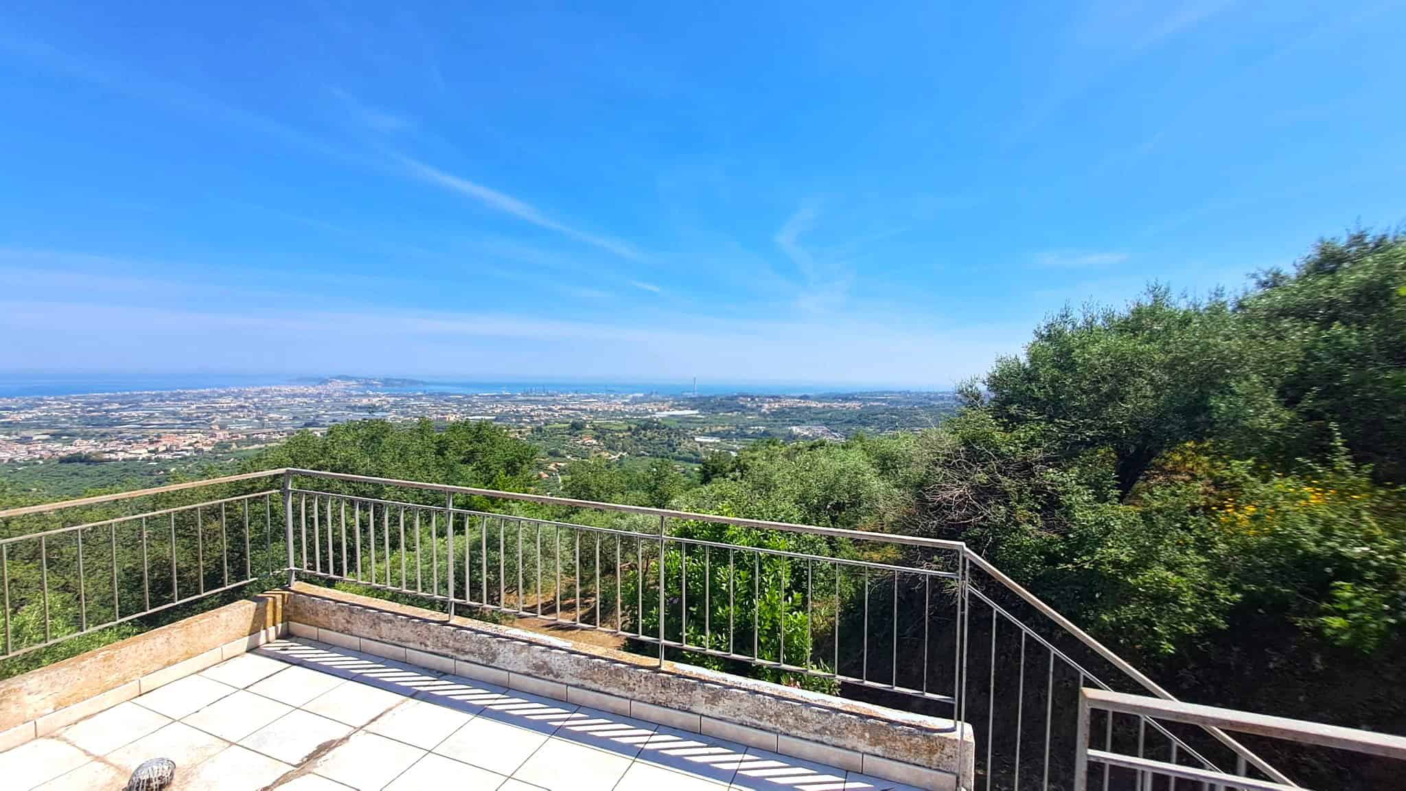 Balcone panoramico con vista sulla città e sulla natura, cielo sereno e paesaggi urbani e verdi, ideale per relax e momenti all'aperto, in un contesto residenziale tranquillo.