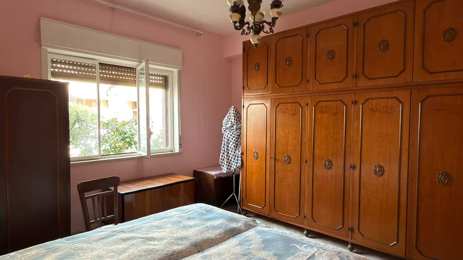 Vano camera con armadio in legno massiccio, finestra luminosa e arredamento classico, ideale per ambienti residenziali e ristrutturazioni di case private.