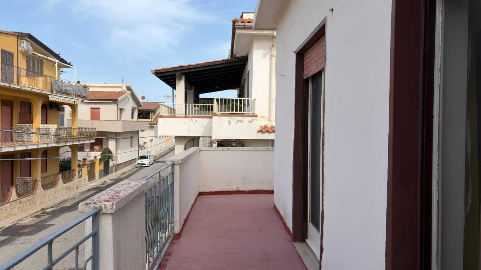 Ampio balcone con vista sulle case di un quartiere residenziale, ideale per relax e momenti all'aperto, con accesso diretto dall'appartamento.