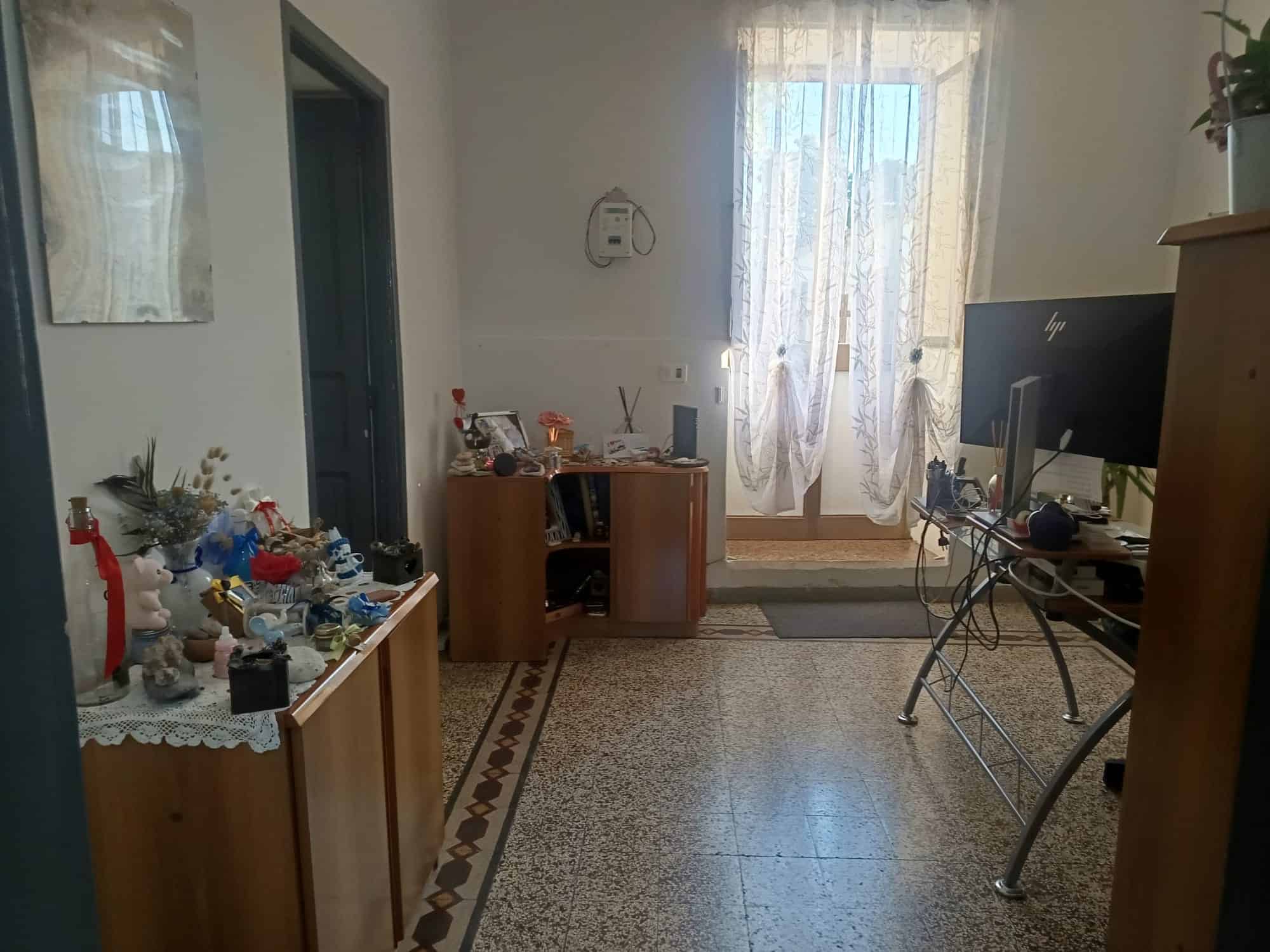 Pannello di controllo con decorazioni natalizie e scrivania con computer in un soggiorno luminoso e accogliente, con tende leggere e pavimento in piastrelle.