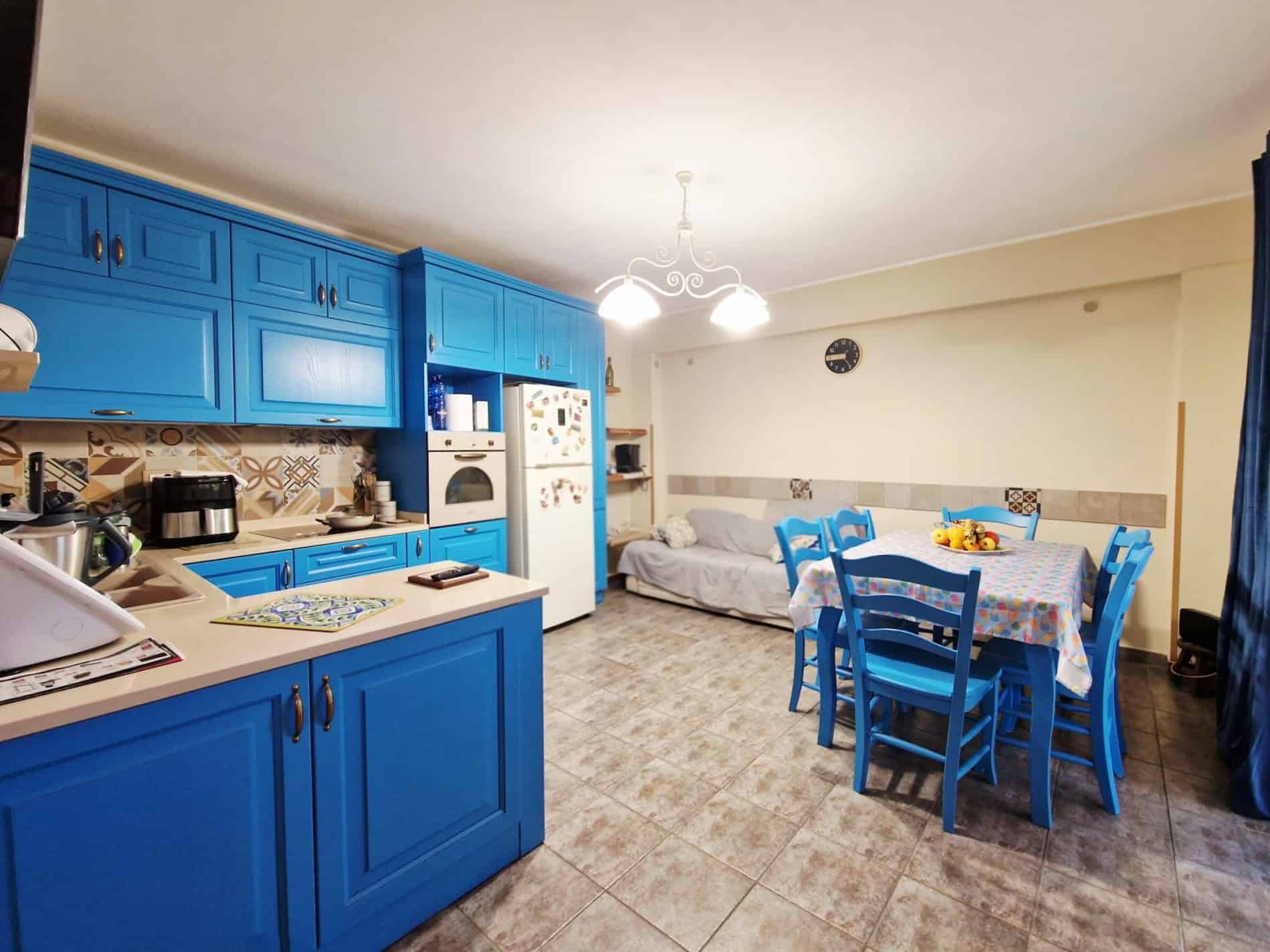 Cucina moderna con mobili blu e zona pranzo con tavolo e sedie, ambiente luminoso e accogliente, ideale per vivere momenti conviviali in casa.