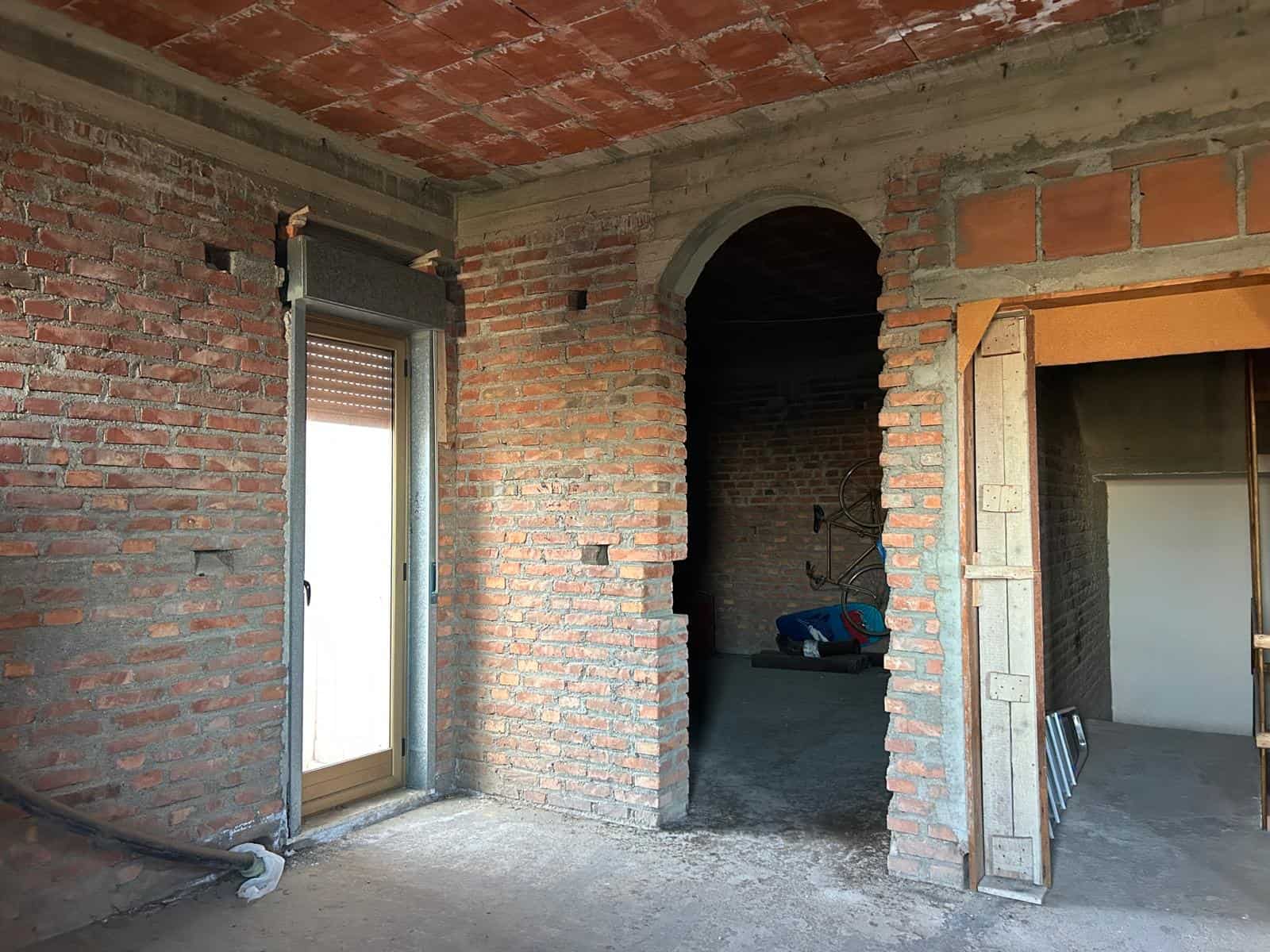 Vano interno in costruzione con pareti in mattoni e arco in muratura, spazio per finiture e installazioni, ambiente di ristrutturazione edilizia, progetto di ristrutturazione casa, lavori di costruzio.