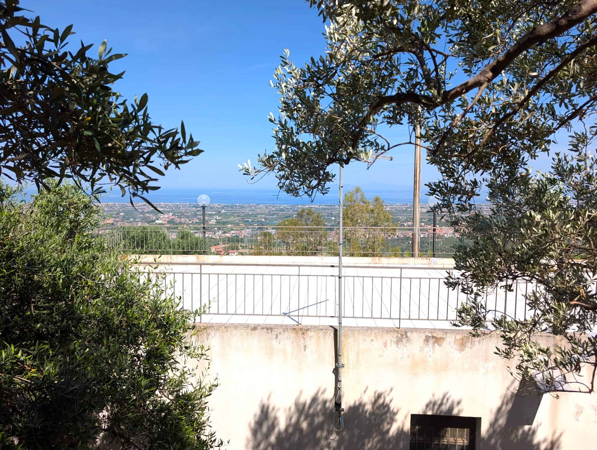 VISTA PANORAMICA DALLA TERRAZZA DI UNA CASA A NEXTCASA, CON PANORAMICA SULLA CITTÀ E IL MARE, CIRCONDATA DA ALBERI E NATURA, IDEALE PER RILASSARSI E GODERE DEL PAESAGGIO.