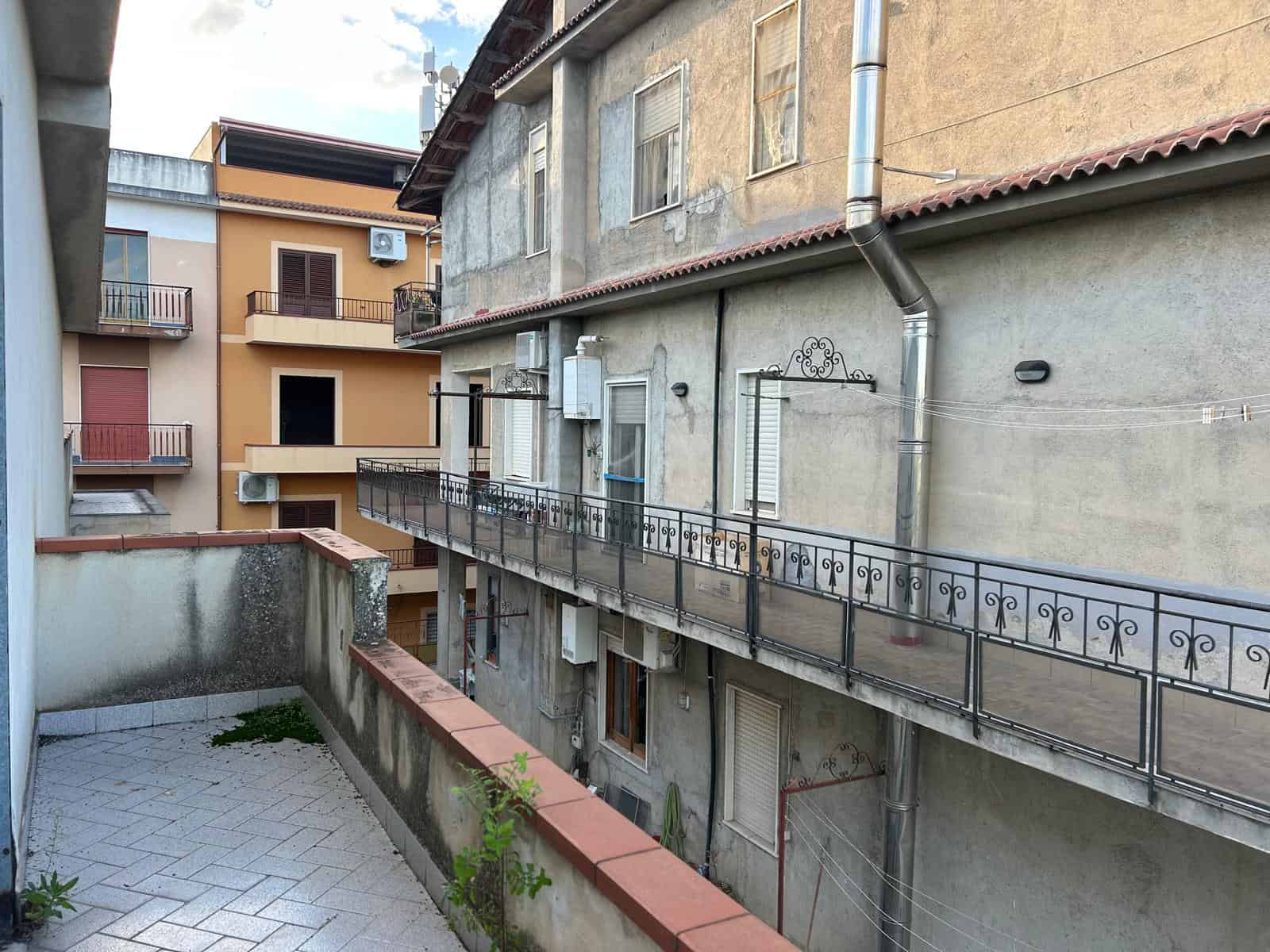 Vista di un cortile condominiale con balconi e facciate di edifici residenziali in zona urbana, con dettagli di ringhiere e finestre.