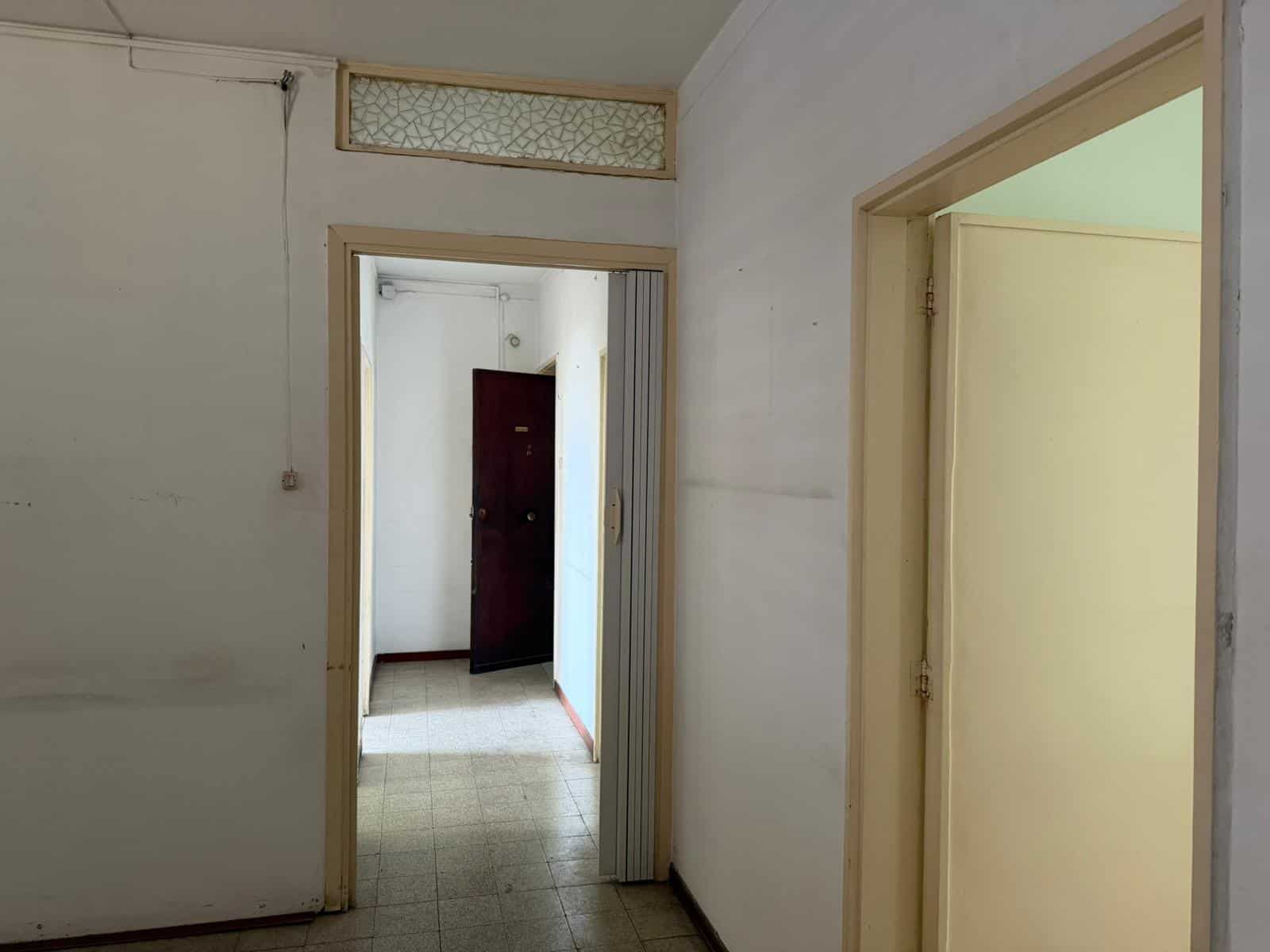 Ampio ingresso con porte interne in legno e pareti bianche, zona di passaggio luminosa e spaziosa, ideale per l'accesso alle varie stanze di un appartamento o ufficio.