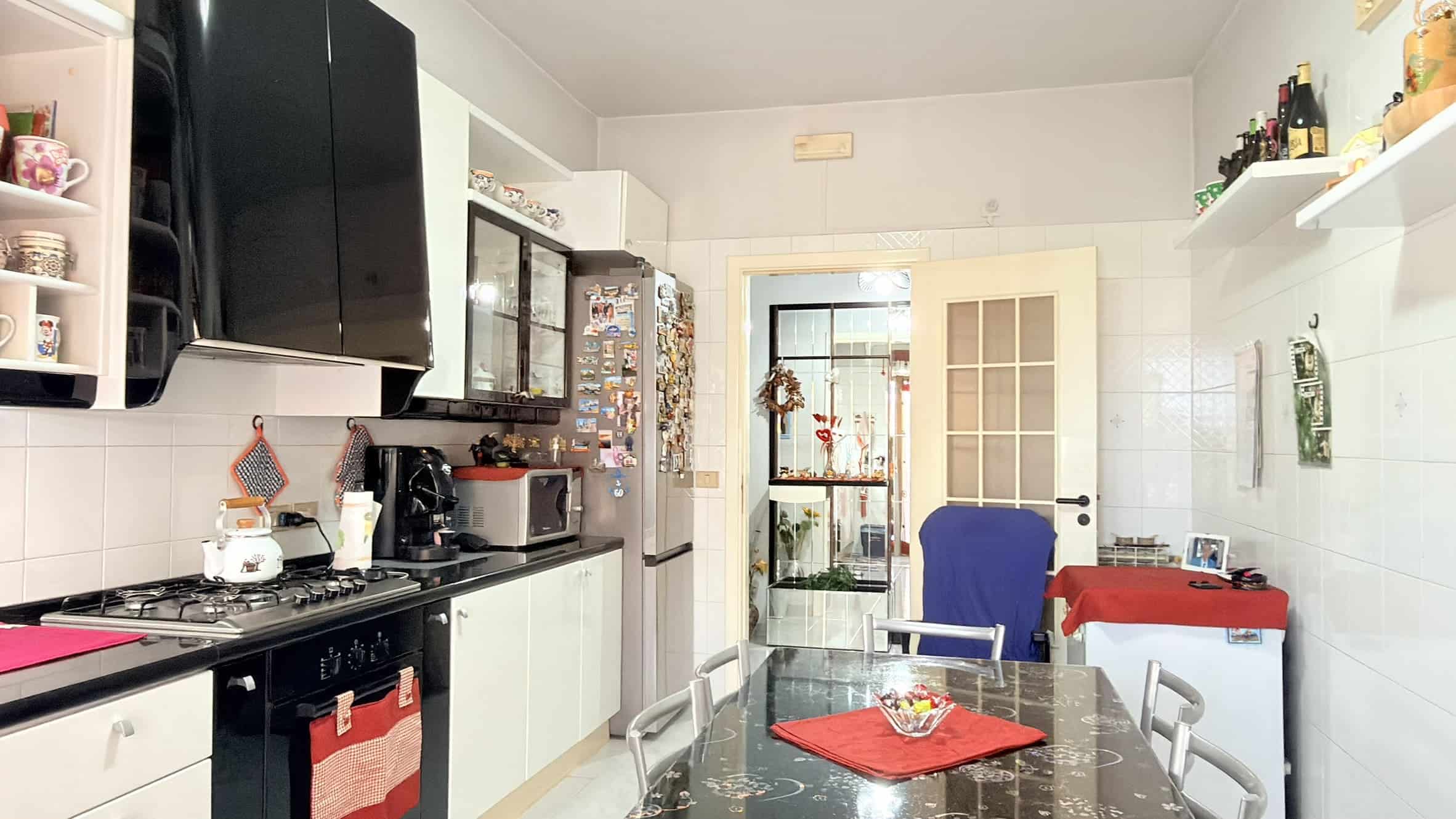 Ampio soggiorno con cucina moderna, elettrodomestici e accessori, spazio luminoso e accogliente, ideale per vivere e cucinare in famiglia o con amici, con dettagli decorativi e mobili funzionali.