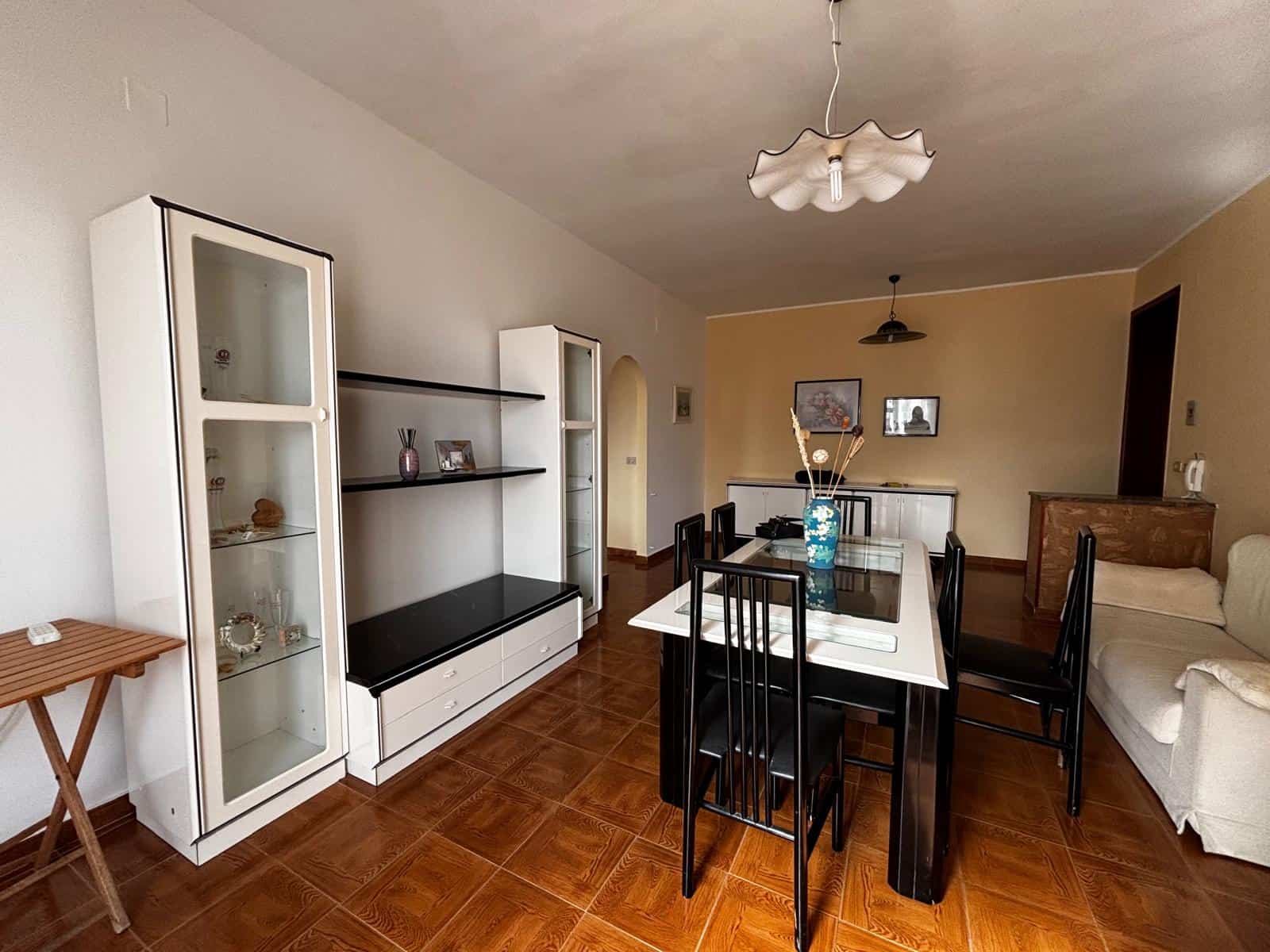 Panca e tavolo da pranzo in soggiorno con mobili moderni, pareti beige e pavimento in ceramica, ambiente accogliente e luminoso, ideale per famiglie e intrattenimento domestico.