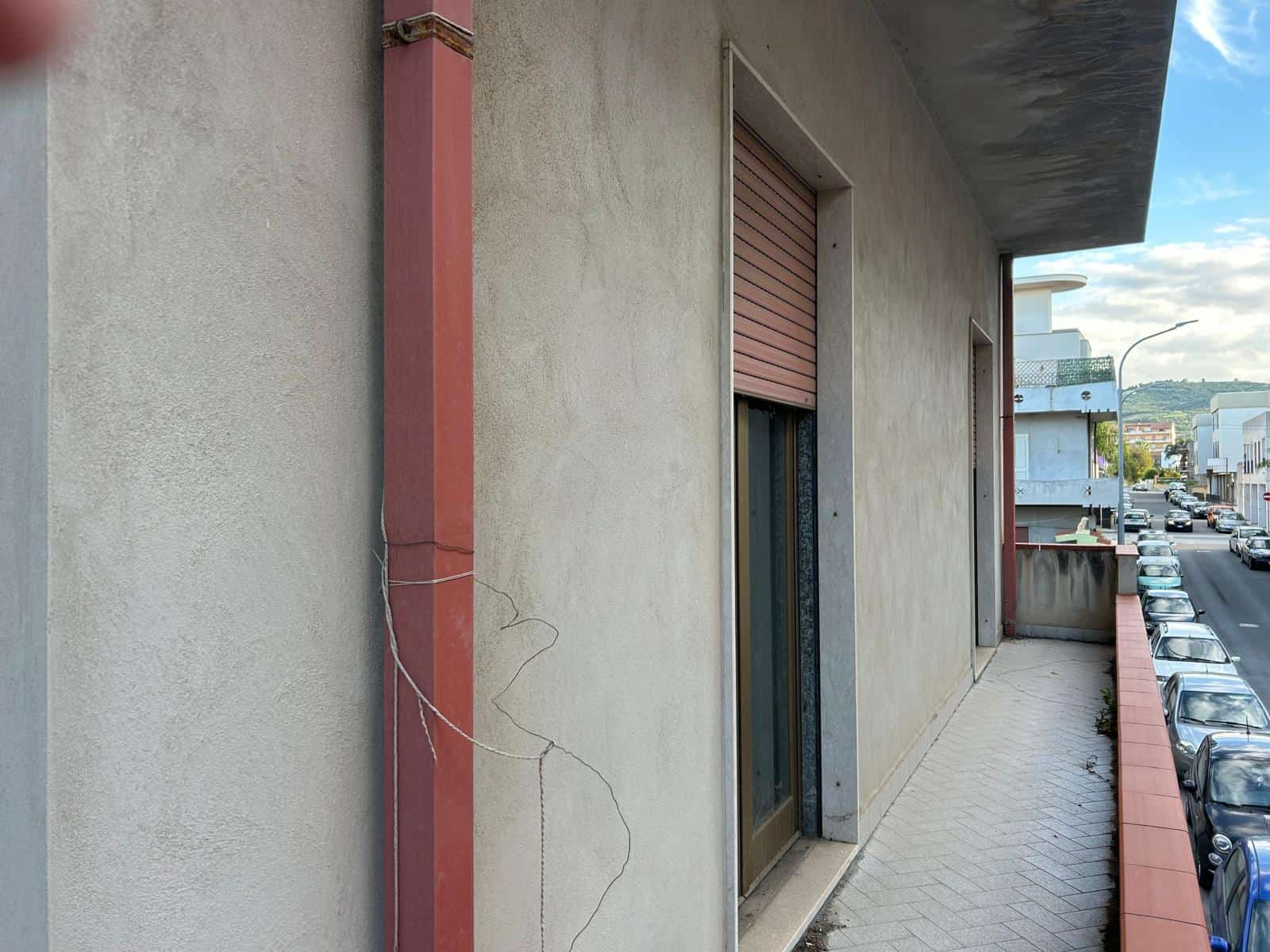 Il sistema di drenaggio e la facciata di un edificio residenziale con balcone, vista laterale, in un contesto urbano.
