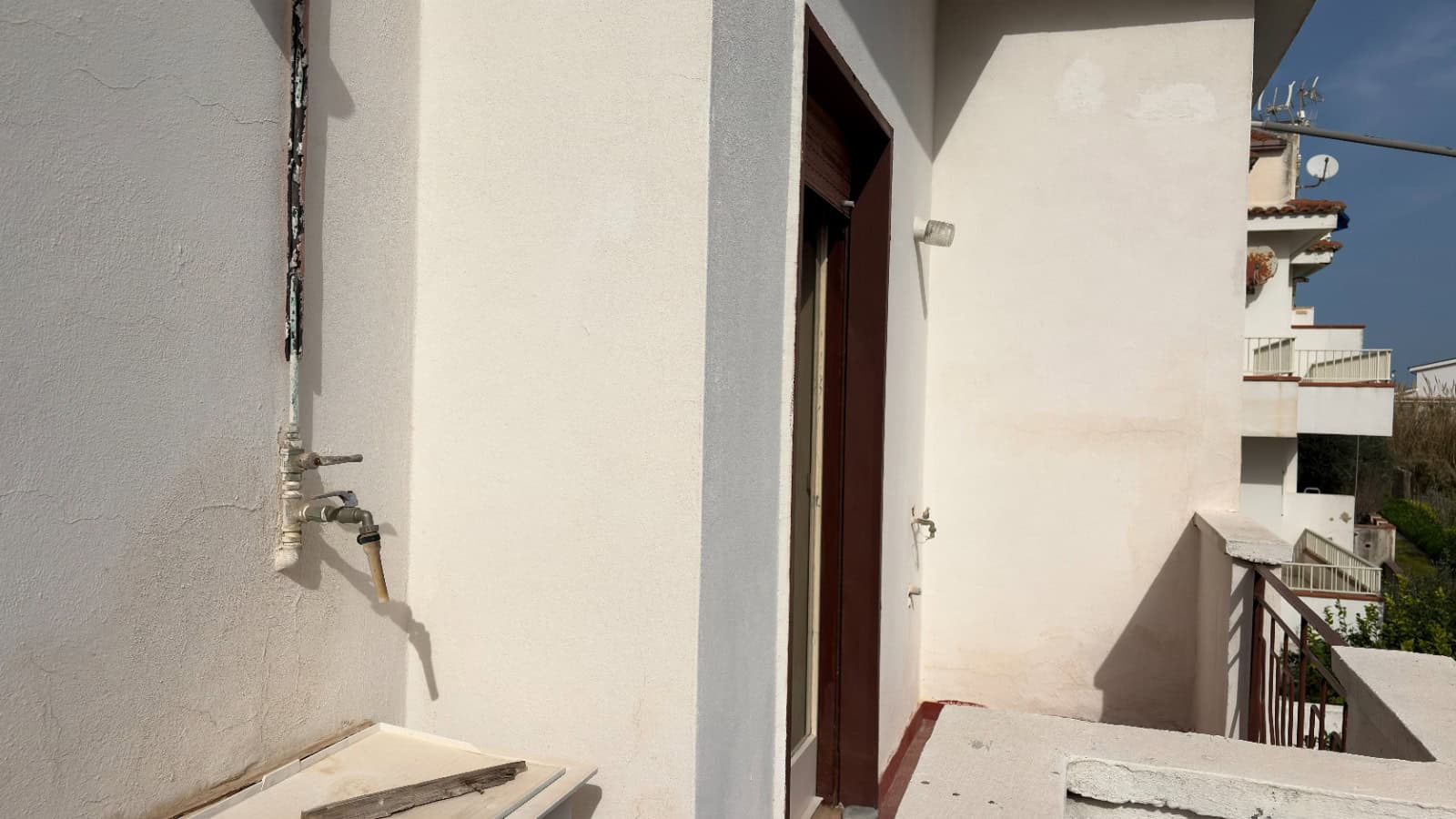 Appartamento con balcone e vista su edifici residenziali, facciata bianca, in zona urbana, in Italia, con dettagli di strutture e balconi.