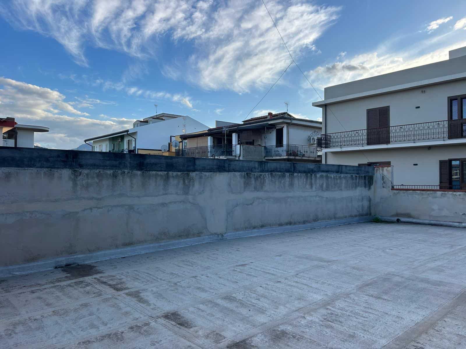 Il tetto di un edificio residenziale con vista sul cielo nuvoloso, in un quartiere urbano, con case moderne e balconi, in Italia.