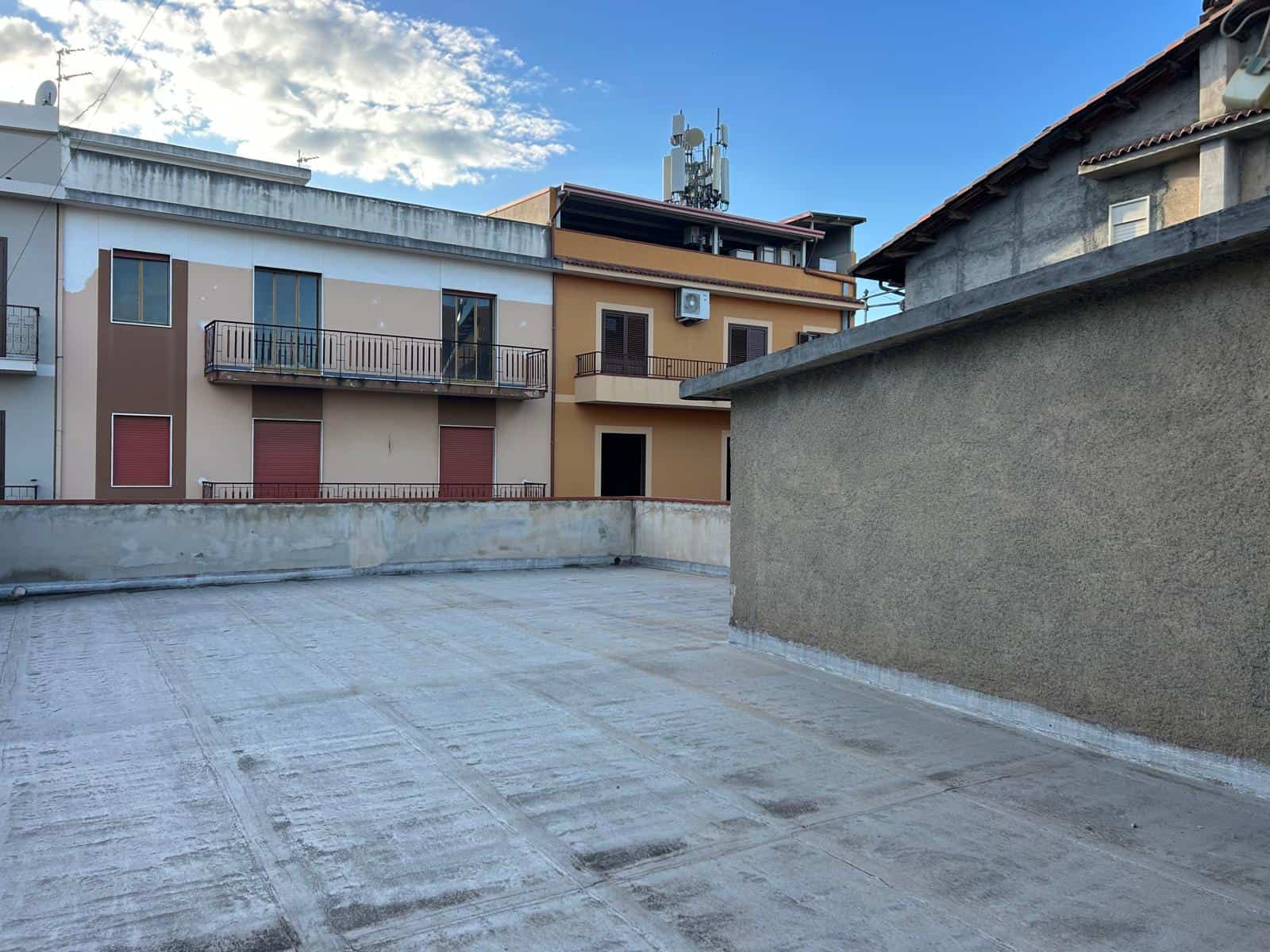 Ampio parcheggio sul tetto di un edificio residenziale con vista su altre abitazioni e cielo sereno, ideale per immobili in vendita o affitto a NextCasa.