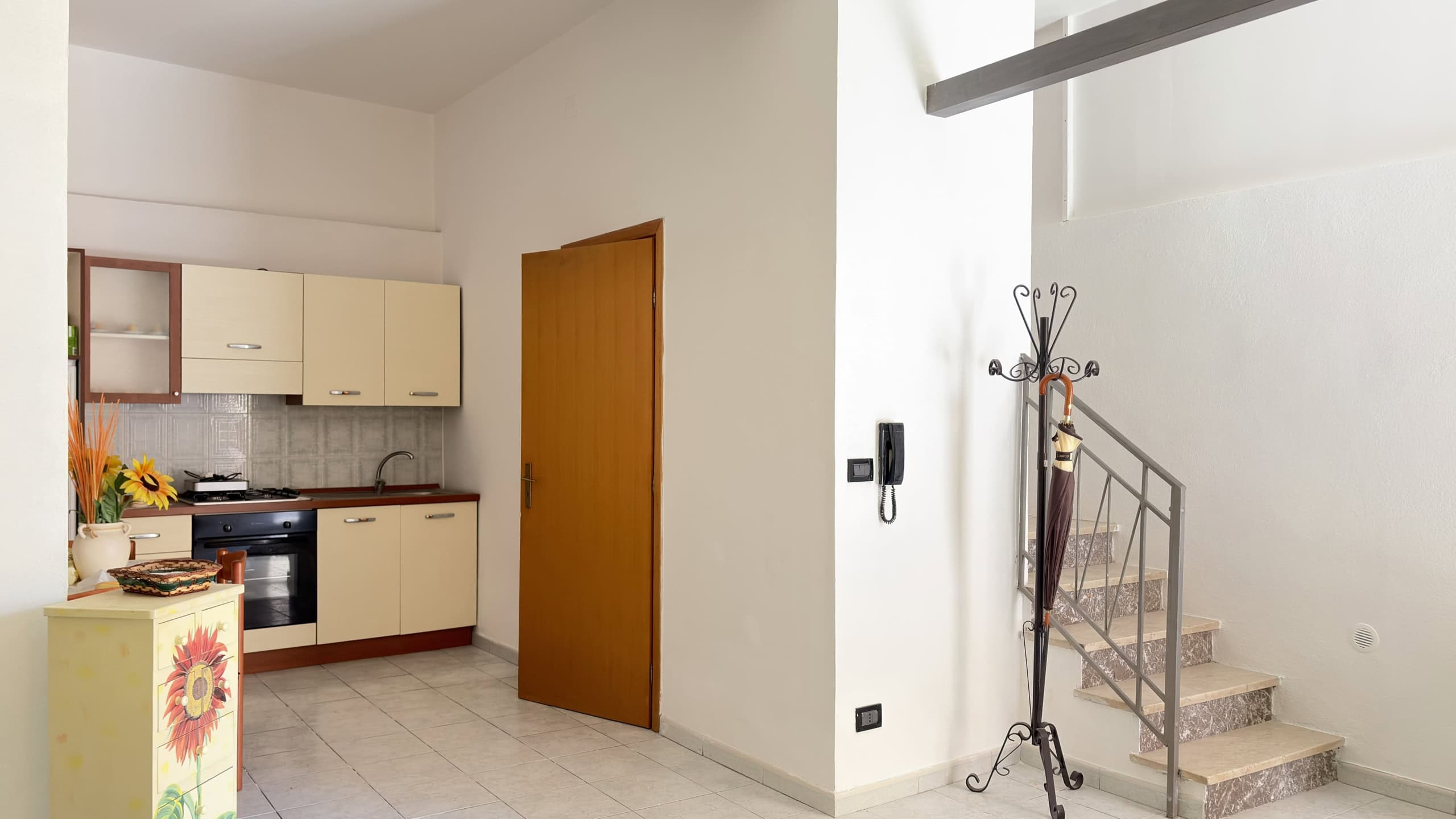 Una cucina moderna e luminosa con mobili beige, piano di lavoro in legno e accessori decorativi, ideale per vivere in un ambiente accogliente e funzionale.