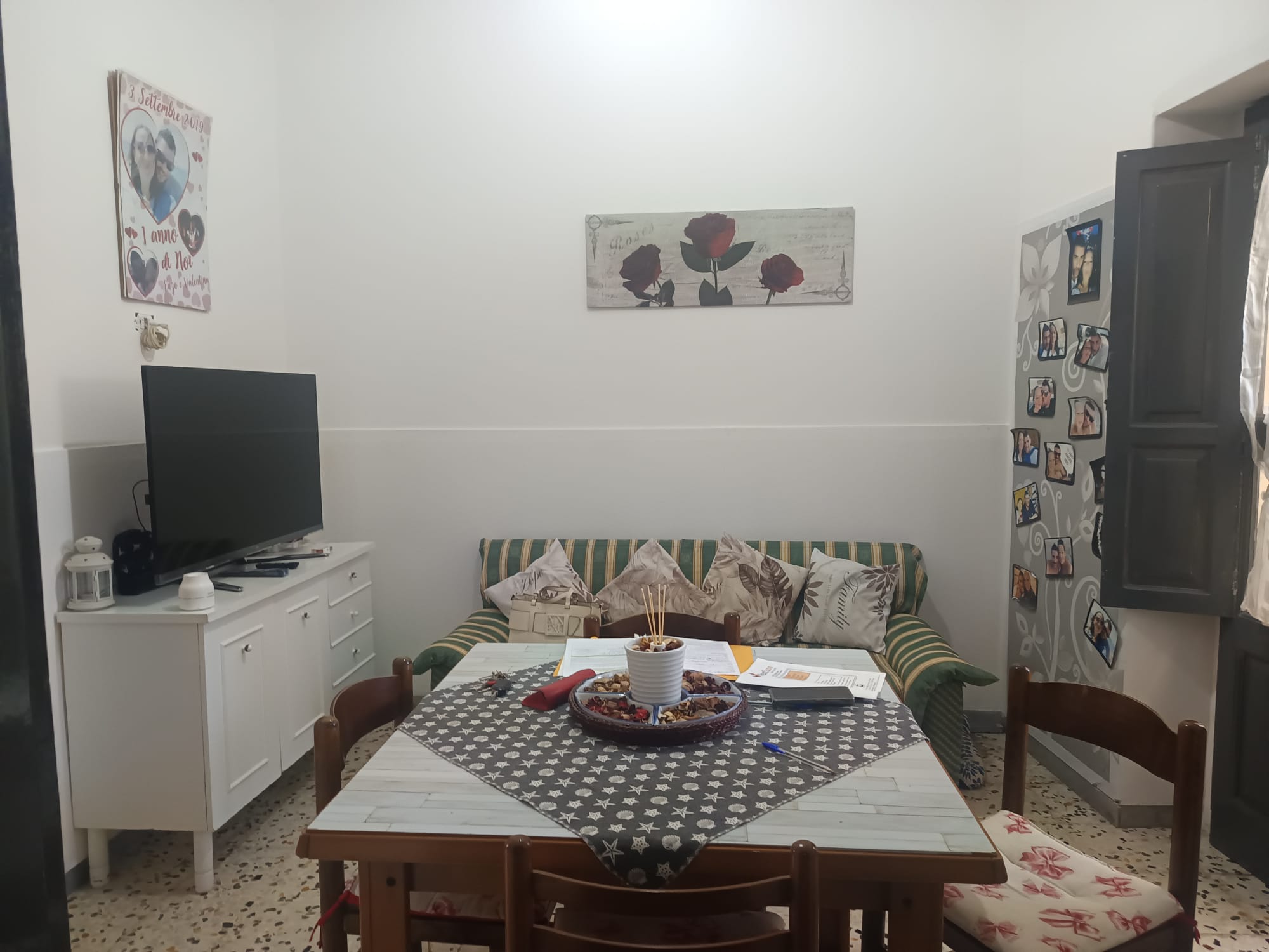 Pannello decorativo con fiori rossi e neri sopra il divano in soggiorno, ambiente accogliente e luminoso con mobili in stile classico, ideale per vivere momenti di relax e convivialità.