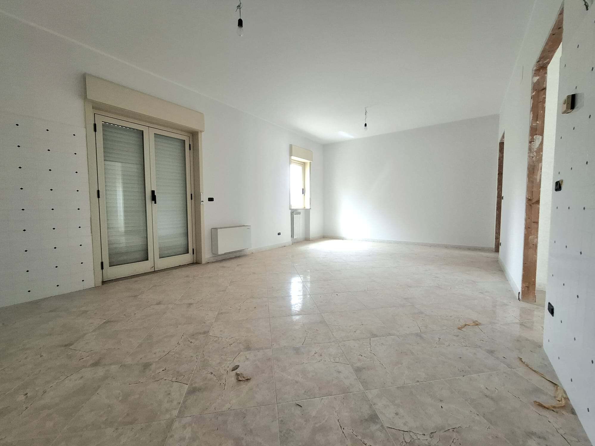 Ampio soggiorno luminoso in appartamento in vendita, con pareti bianche e grandi finestre, ideale per vivere e arredare con stile.