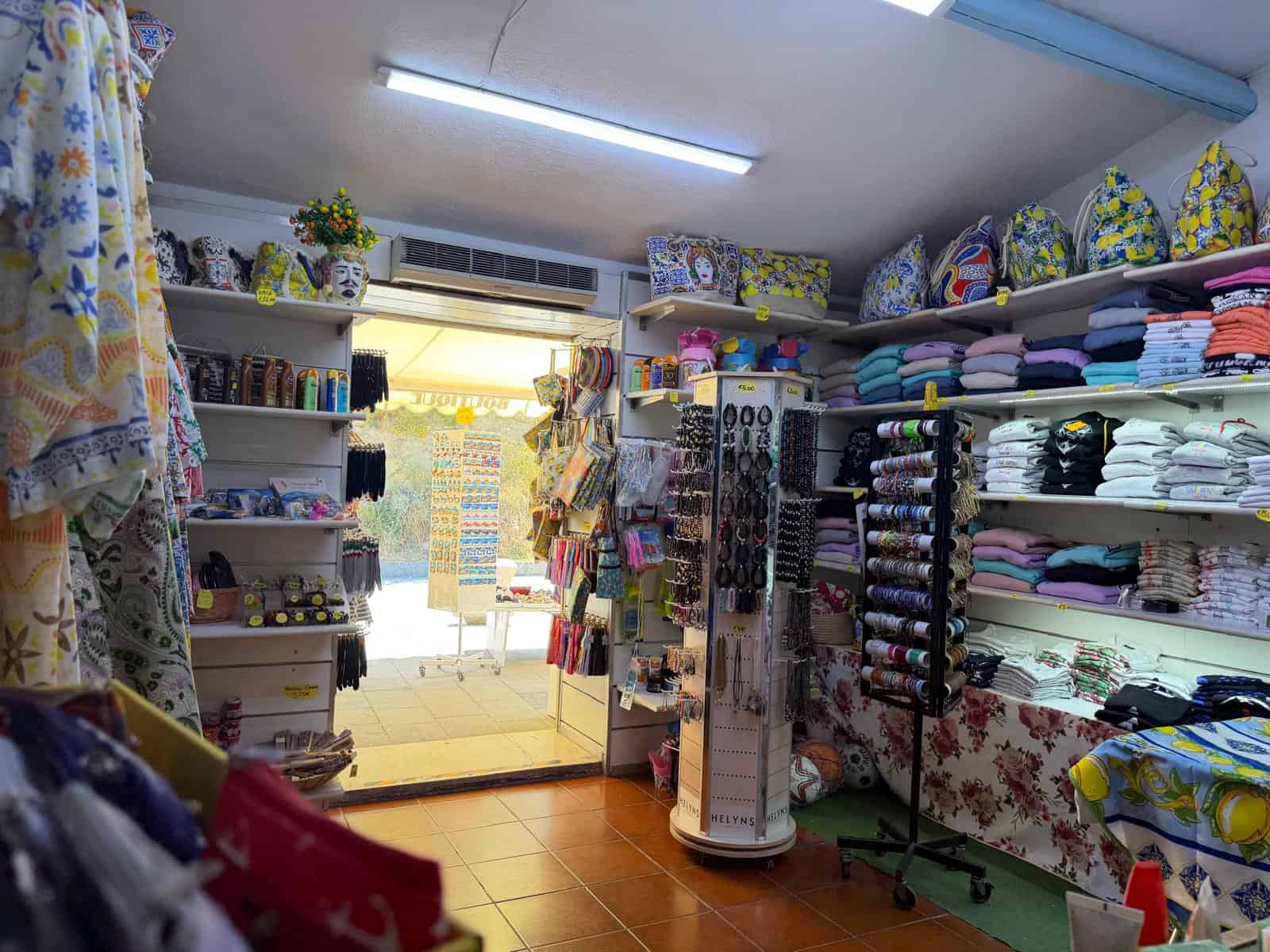 Negozio di tessuti e articoli per la casa con scaffali pieni di stoffe colorate, decorazioni e accessori per il cucito, ambiente luminoso e accogliente.